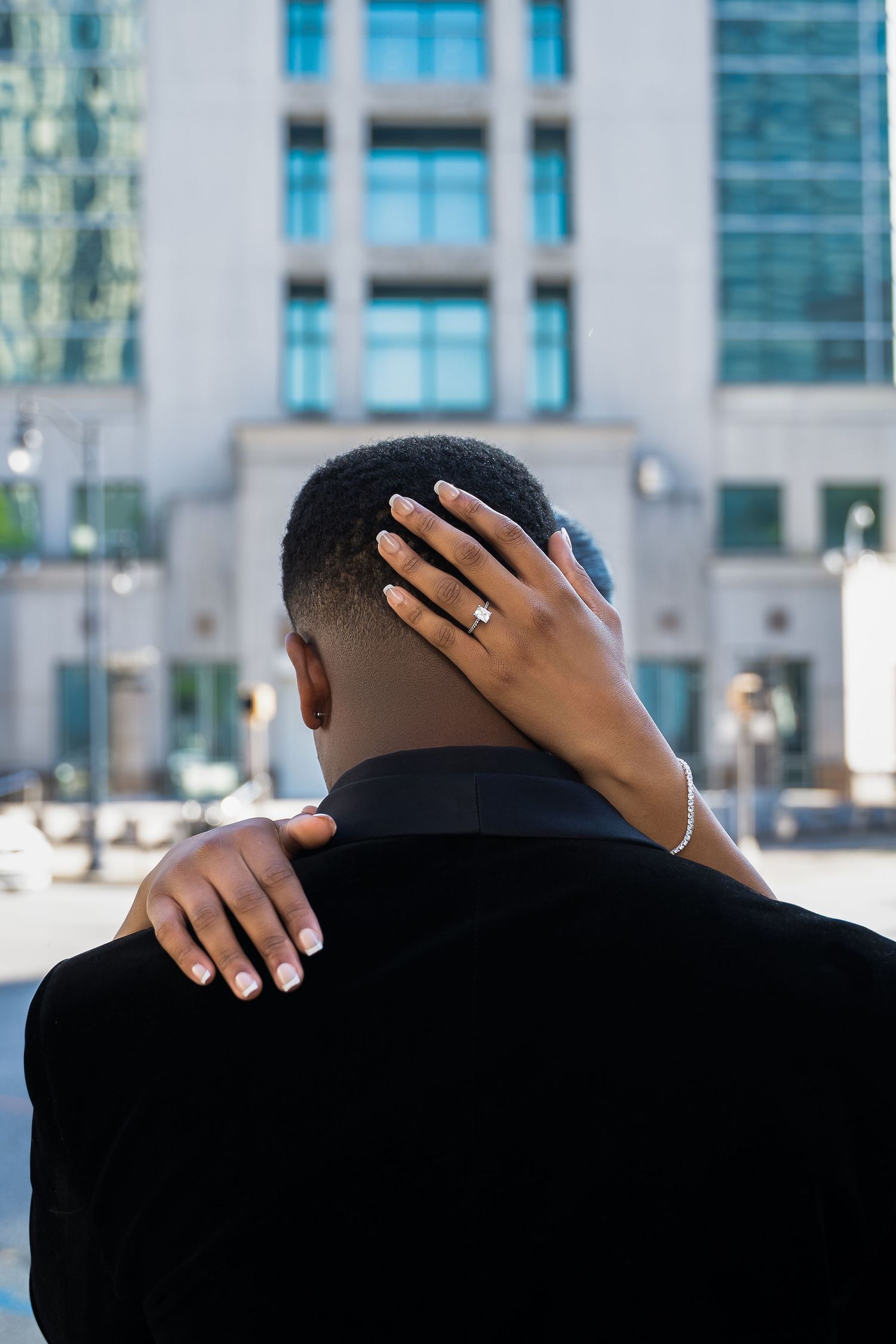 A back view of someone in a suit with hands embracing from behind.