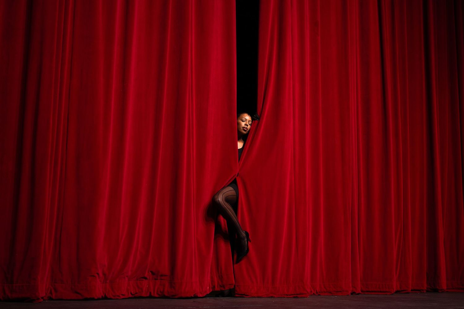 Red stage curtain with dramatic lighting and shadows.