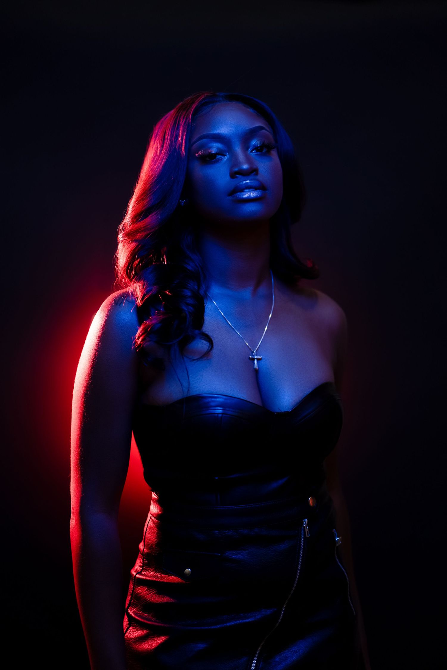 Moody portrait with dramatic red and blue lighting in dark setting.