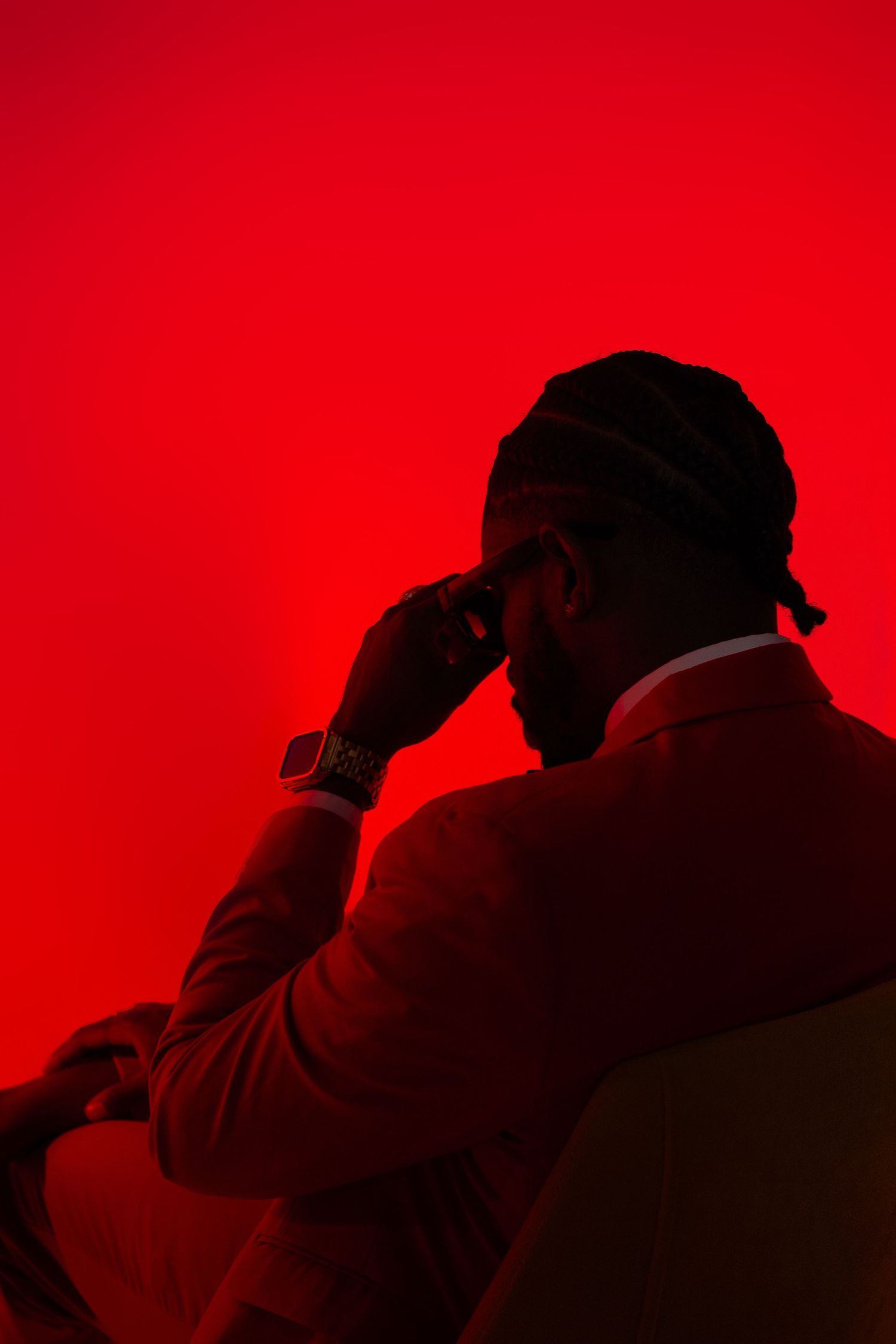 Silhouetted figures against a bright red background in an artistic photo series.