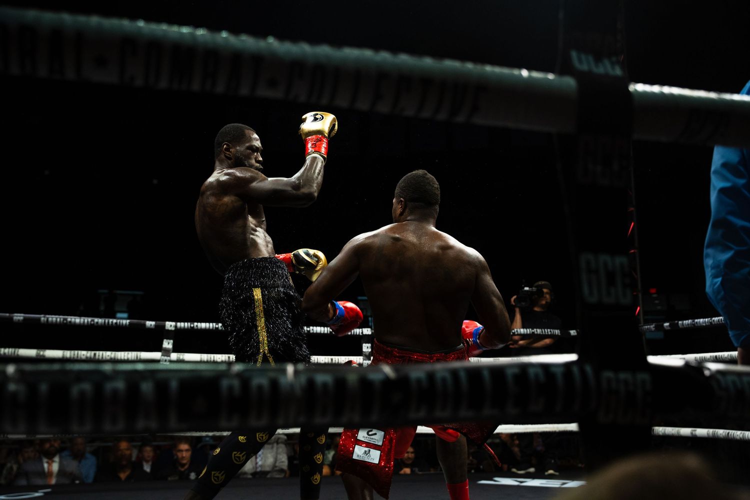 Dark silhouettes of boxing action in a dimly lit boxing ring.