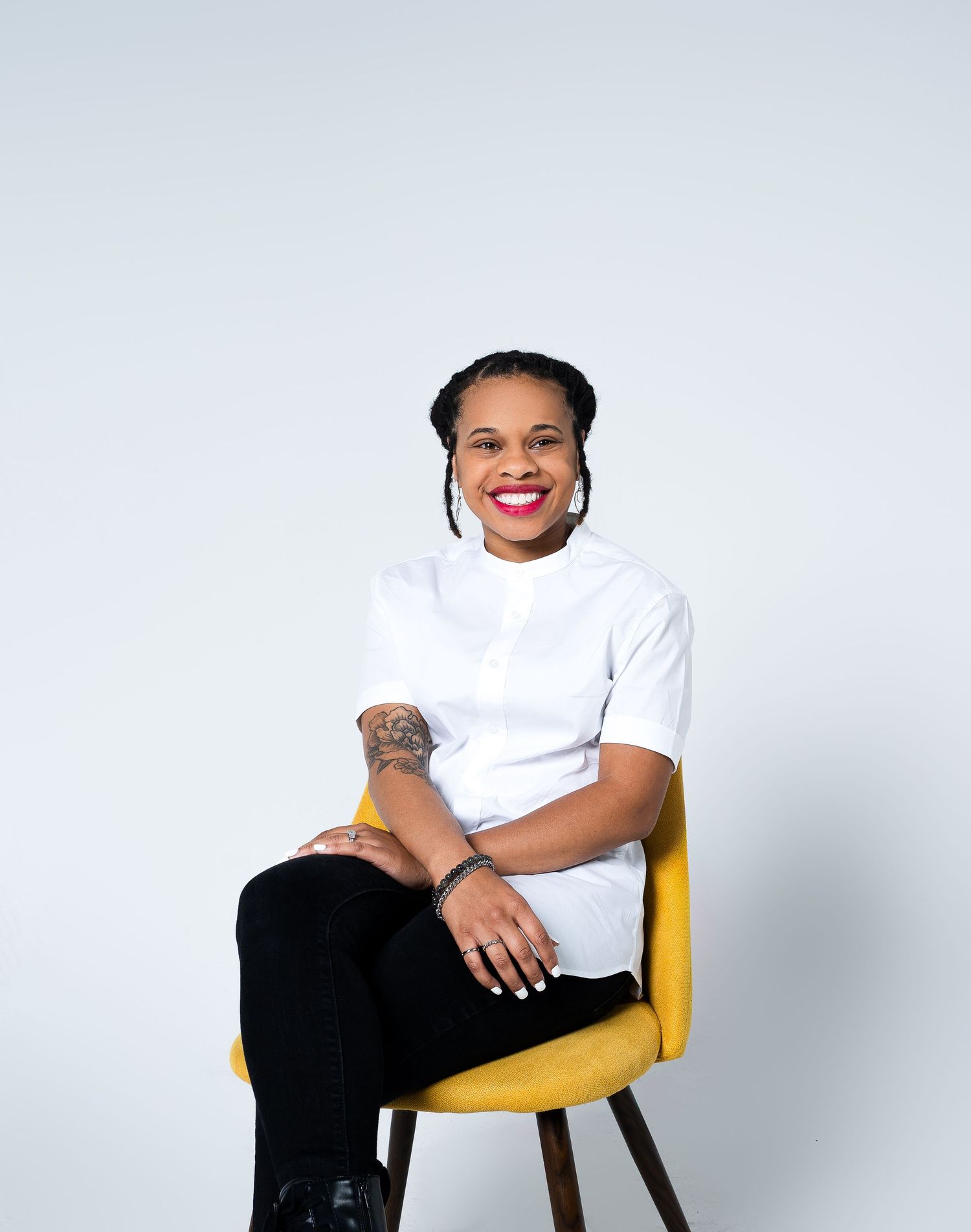 Person in white t-shirt poses on yellow chair against white background.