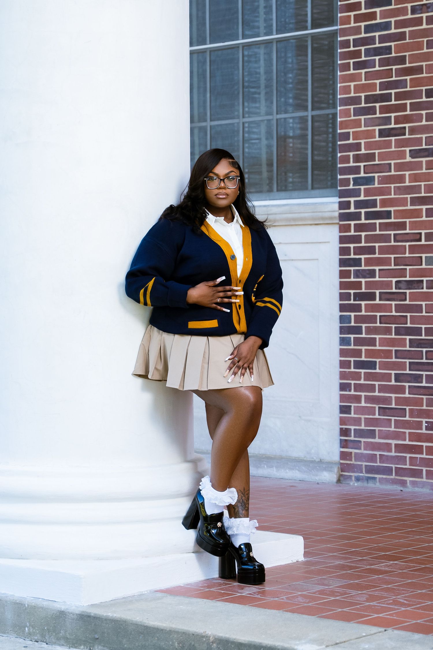 Student in navy and yellow varsity uniform poses on white colonial building steps.