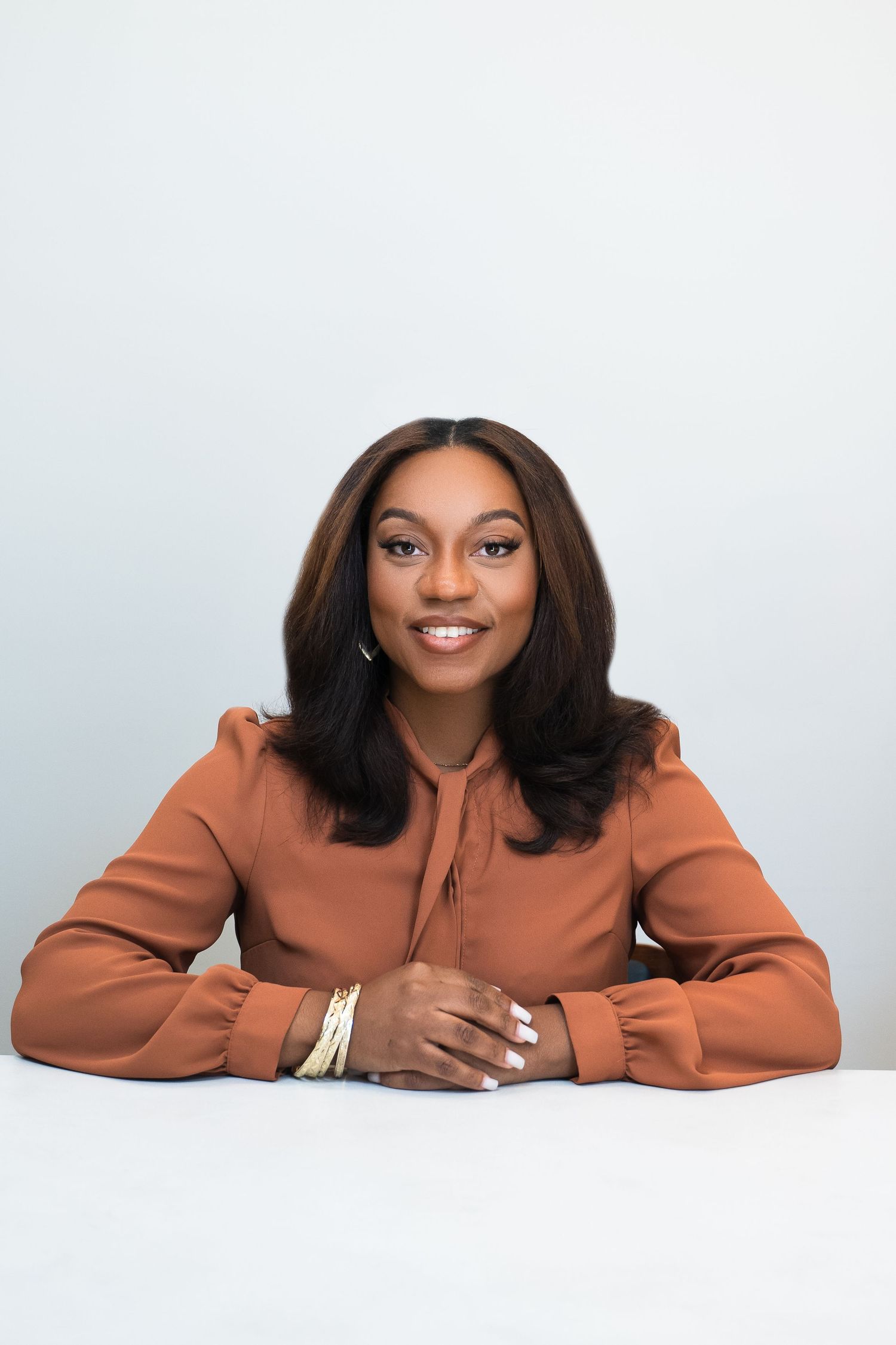 Professional portrait in rust-colored blouse against white background.
