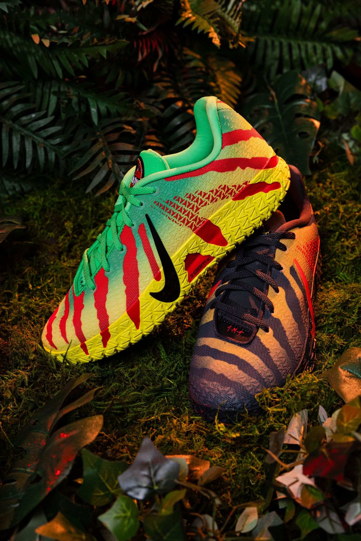 Nike soccer cleats with vibrant jungle-inspired multicolor design displayed on moss and tropical foliage.