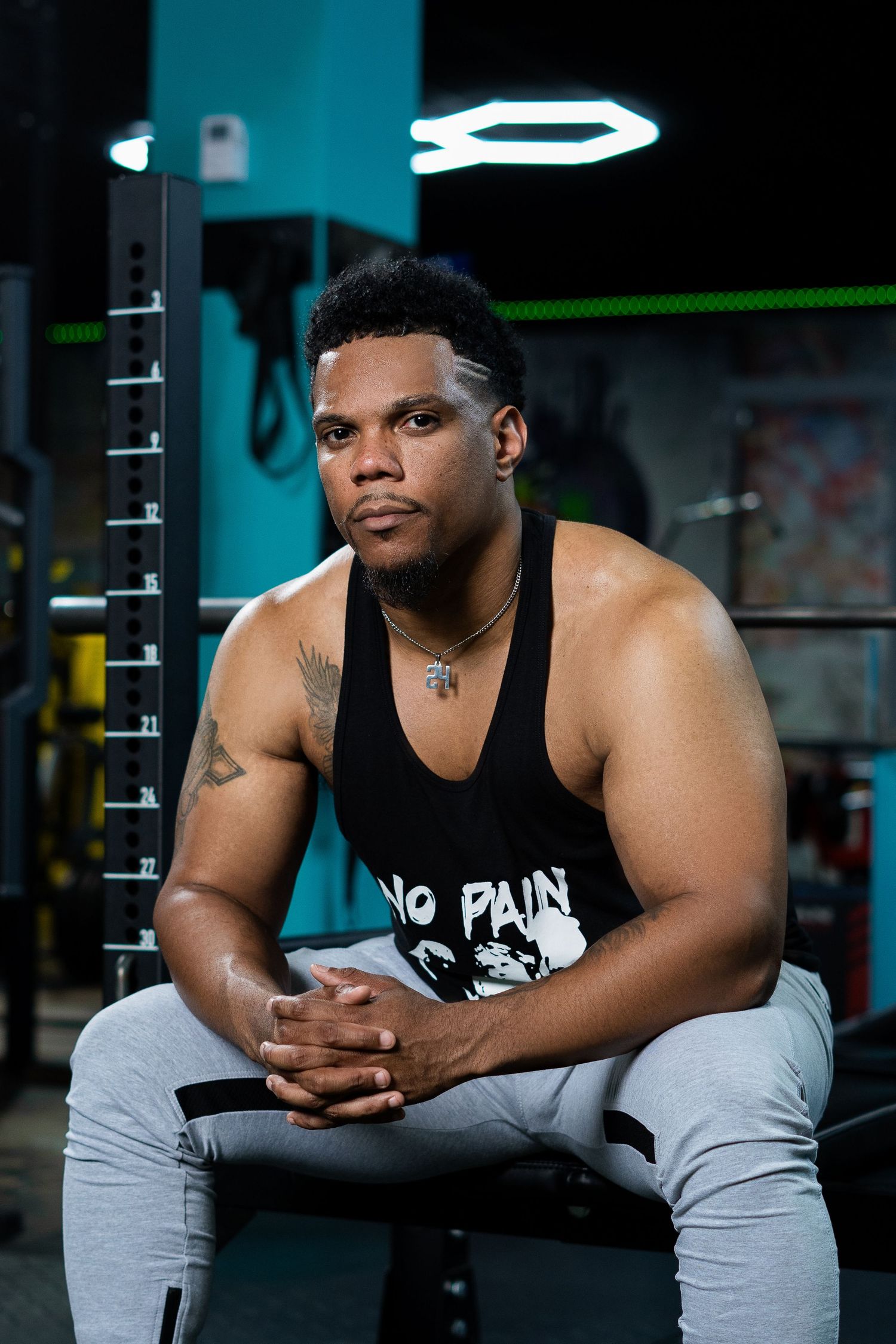Athletic person in workout attire resting on bench between sets at gym.
