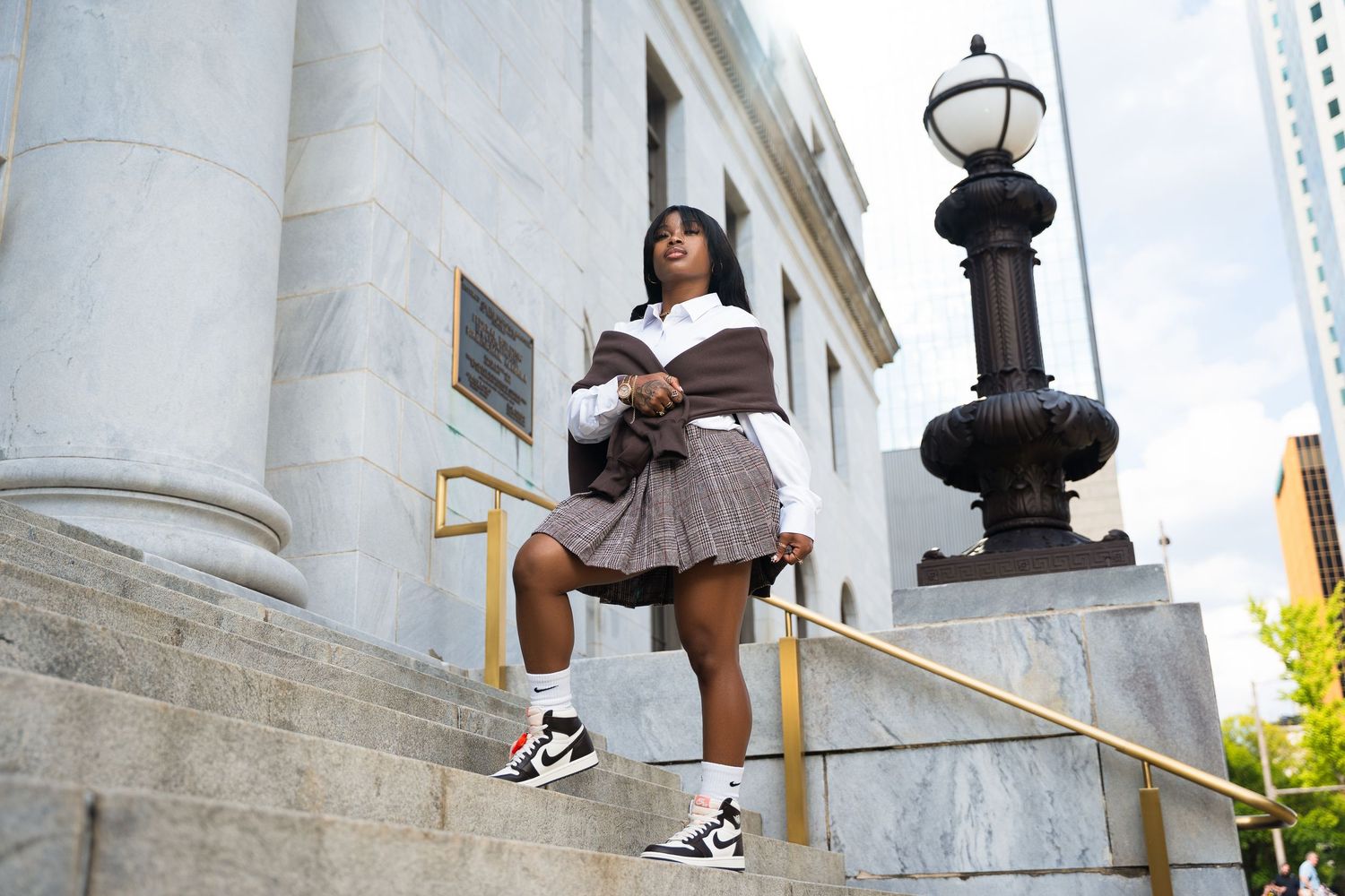 Person sitting on white marble steps wearing casual sneakers and shorts in a sunny outdoor setting.