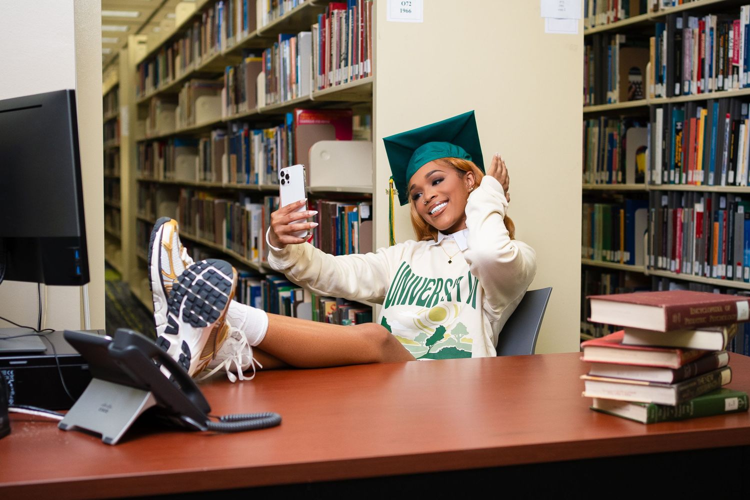 Student studying with textbooks and laptop in library study area.