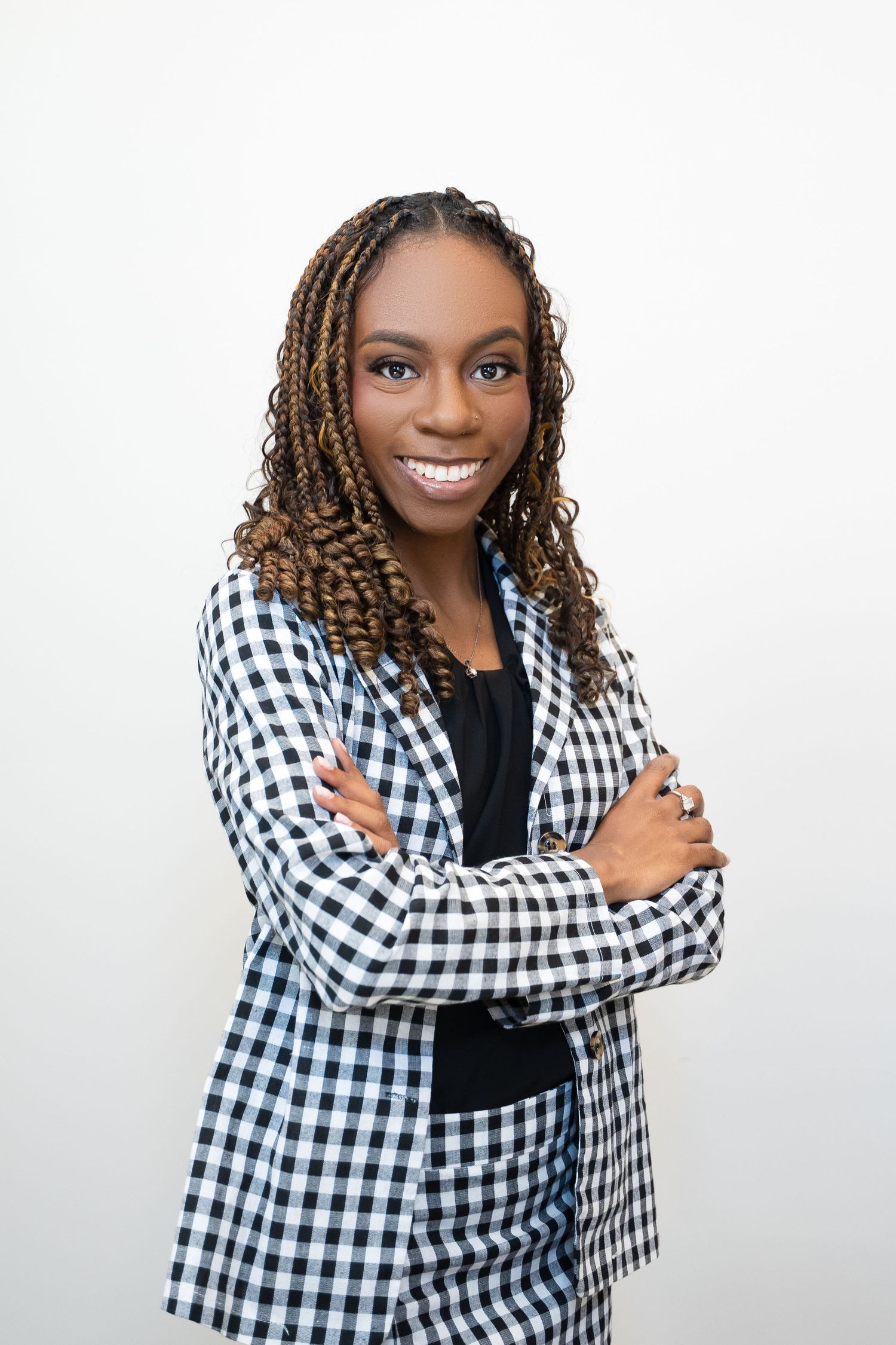 Professional photoshoot featuring black and white gingham blazer styled with a dark top against white background.