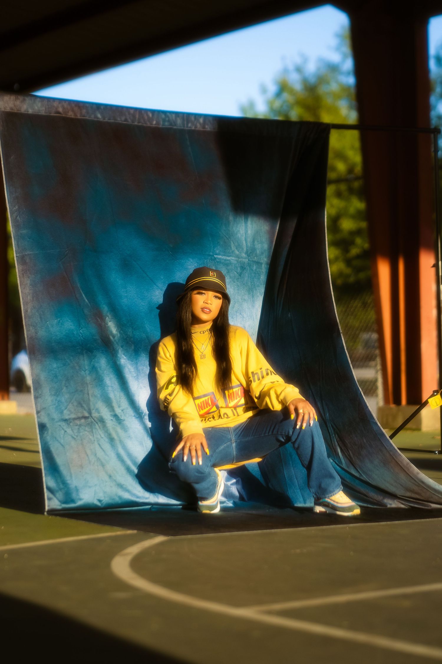 Street style fashion photo with blue backdrop and casual yellow outfit.