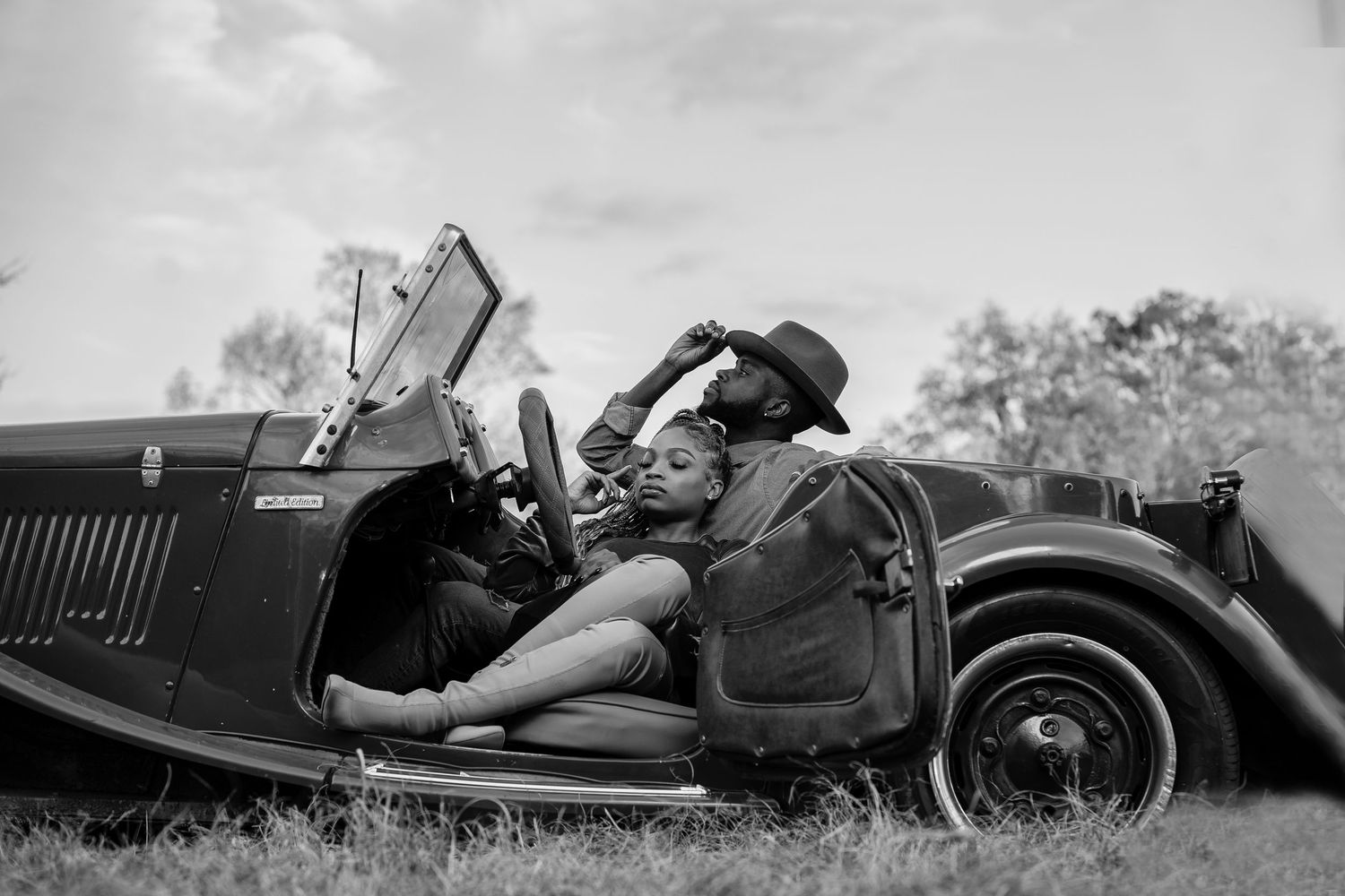 Vintage black and white photo of someone relaxing in a classic convertible car.