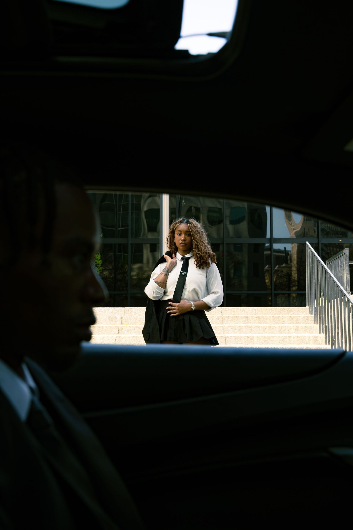 Dark silhouettes of people embracing are visible through a car window at night.