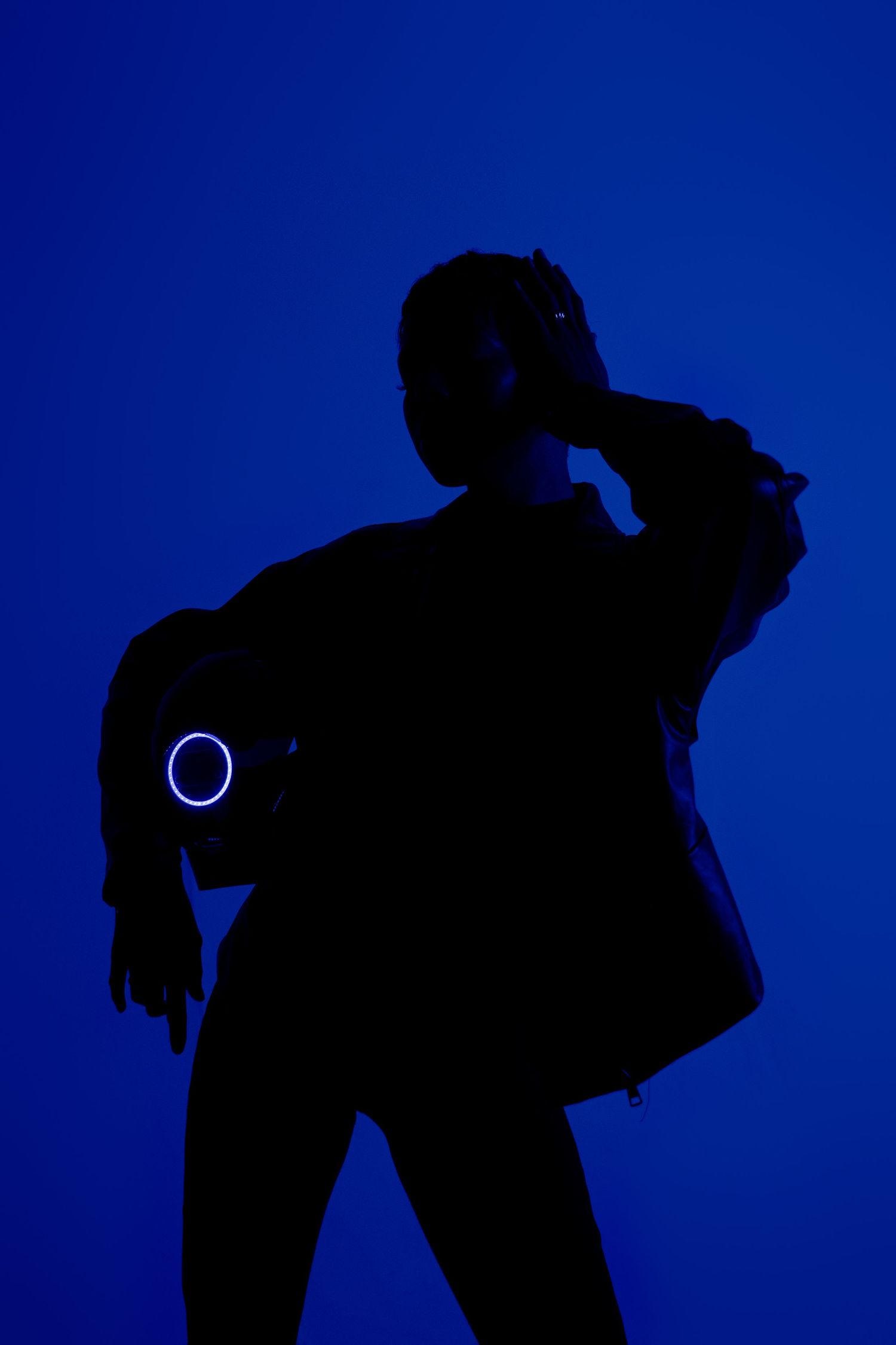 Silhouette of a figure with glowing ring detail against deep blue background.