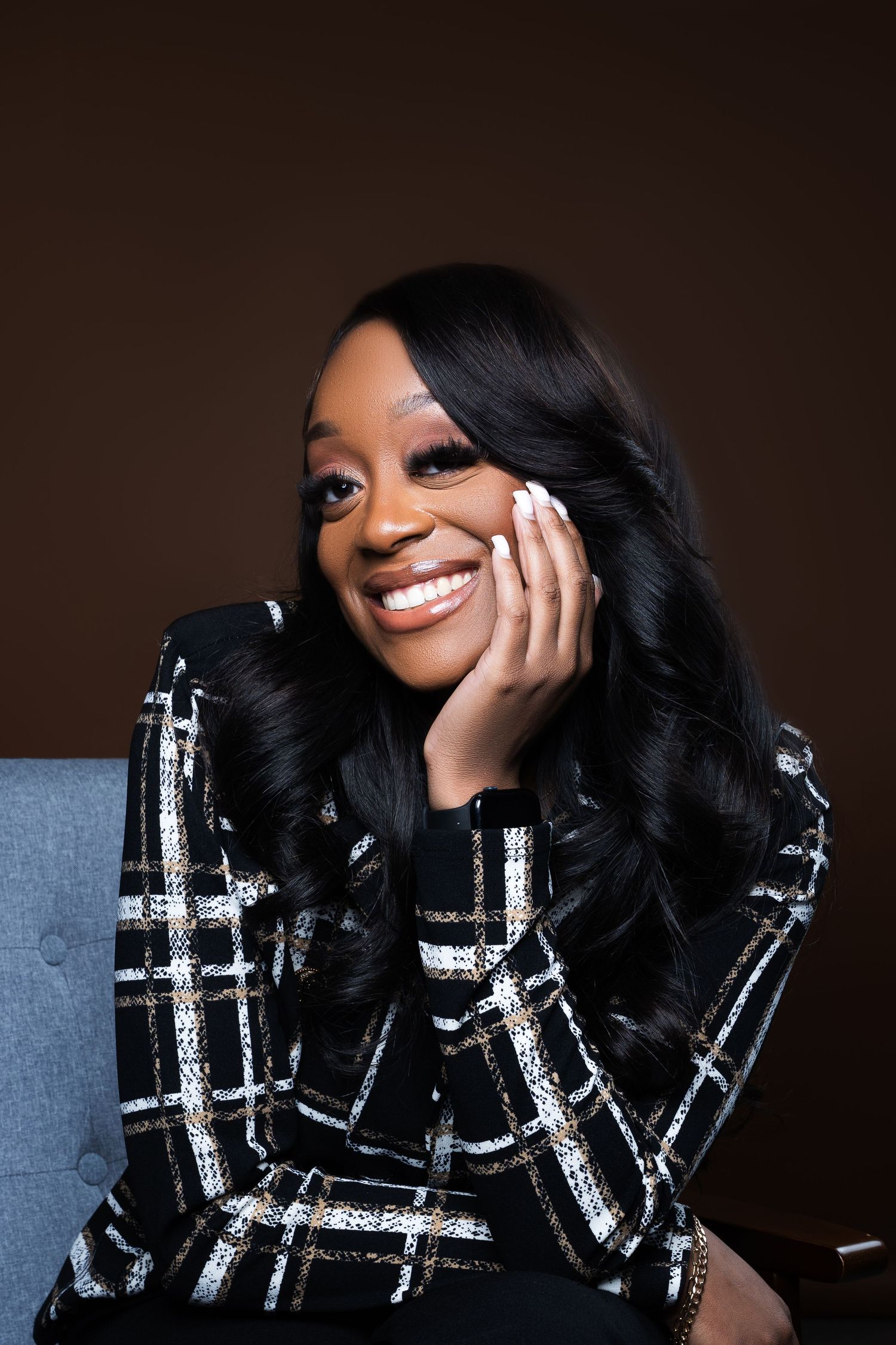 Studio portrait featuring black and white patterned jacket and genuine smile.