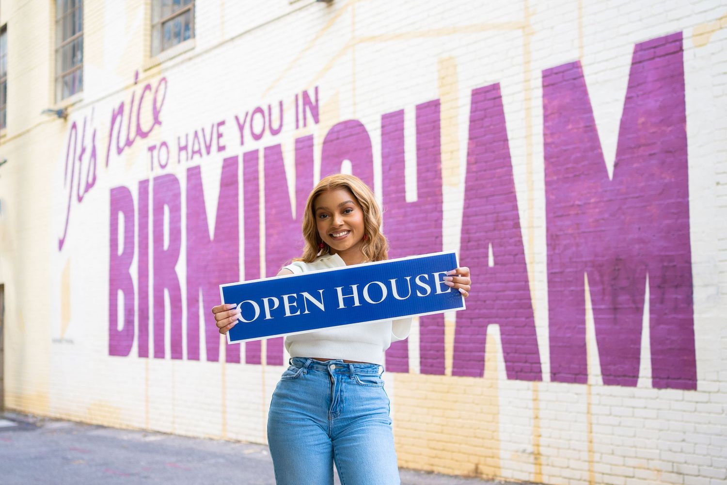 Purple Birmingham wall mural serves as backdrop for real estate open house sign.