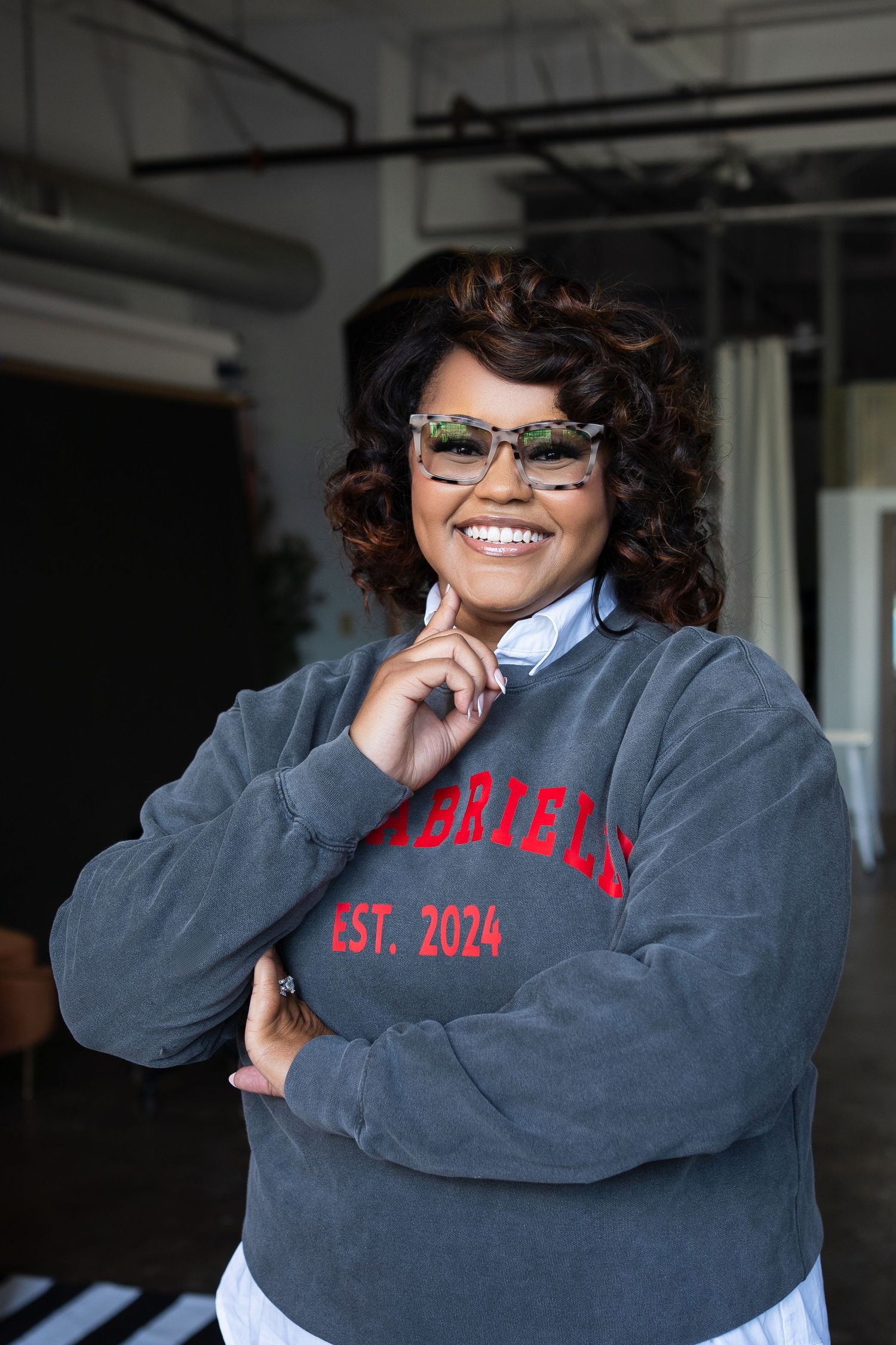 Casual portrait in gray university sweatshirt and glasses with industrial background.
