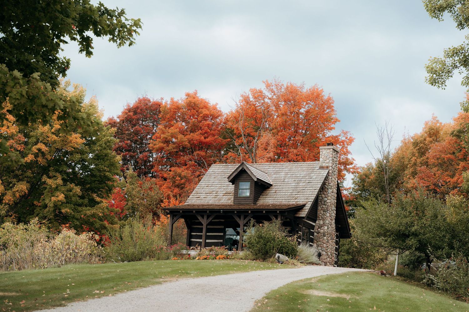 Rustic barn venue surrounded by vibrant autumn foliage on a scenic hillside.