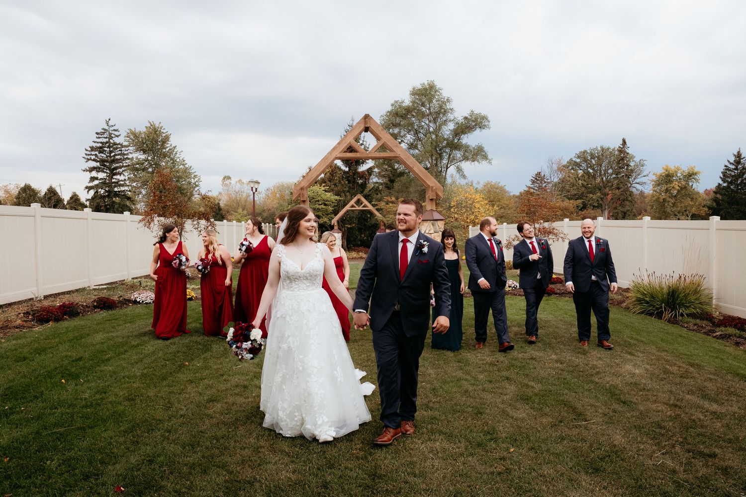 Wedding party gathered on a grassy hillside during an autumn celebration.