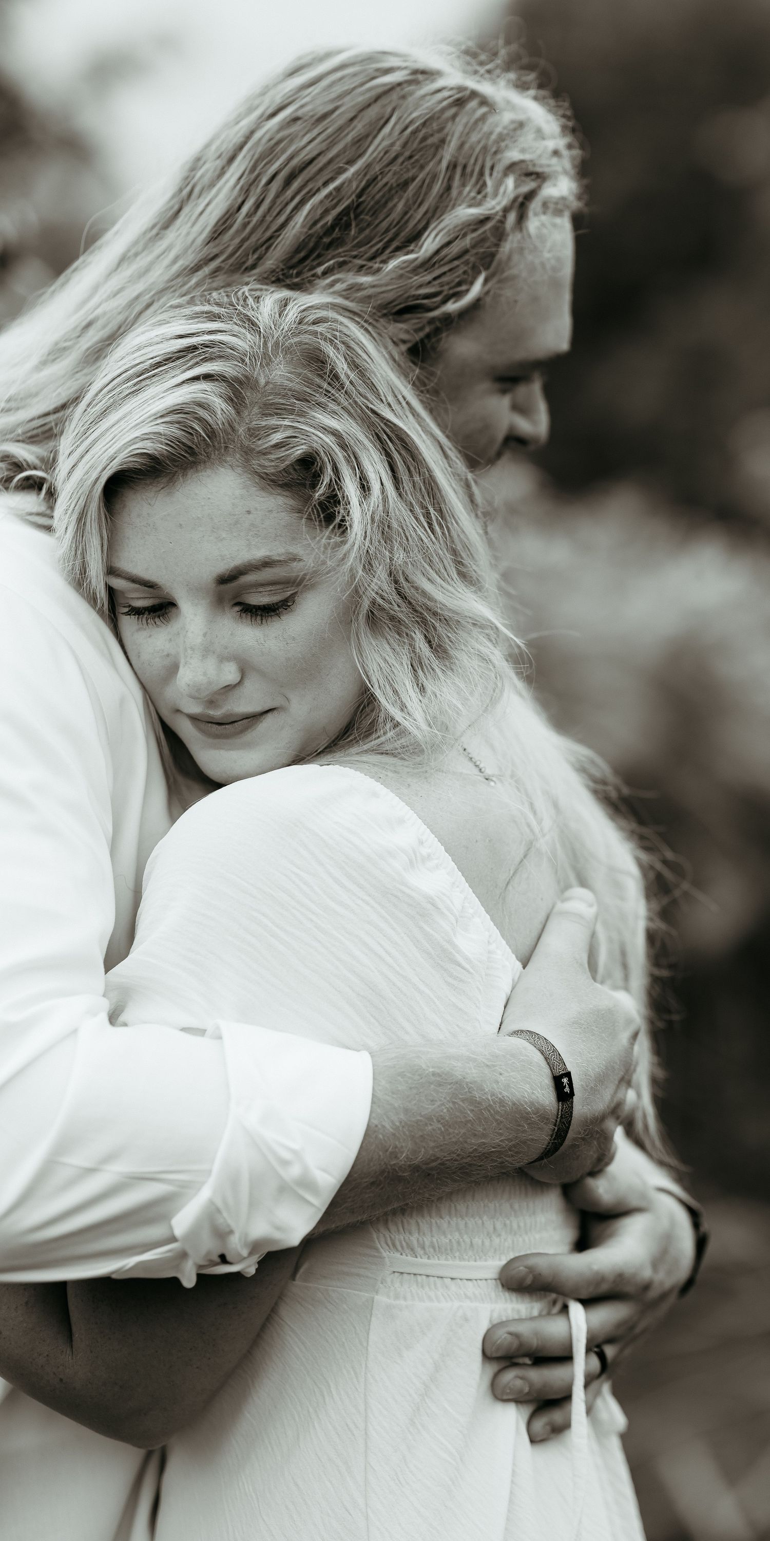 An intimate black and white portrait of a couple embracing in romantic lighting.