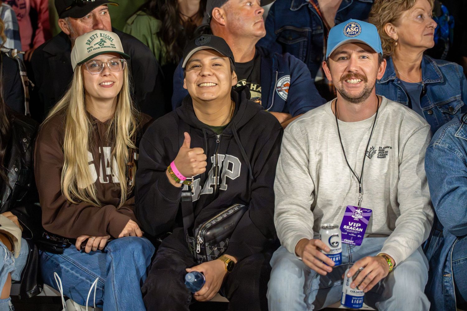 Crowd of sports fans watching a game together in stadium seating.