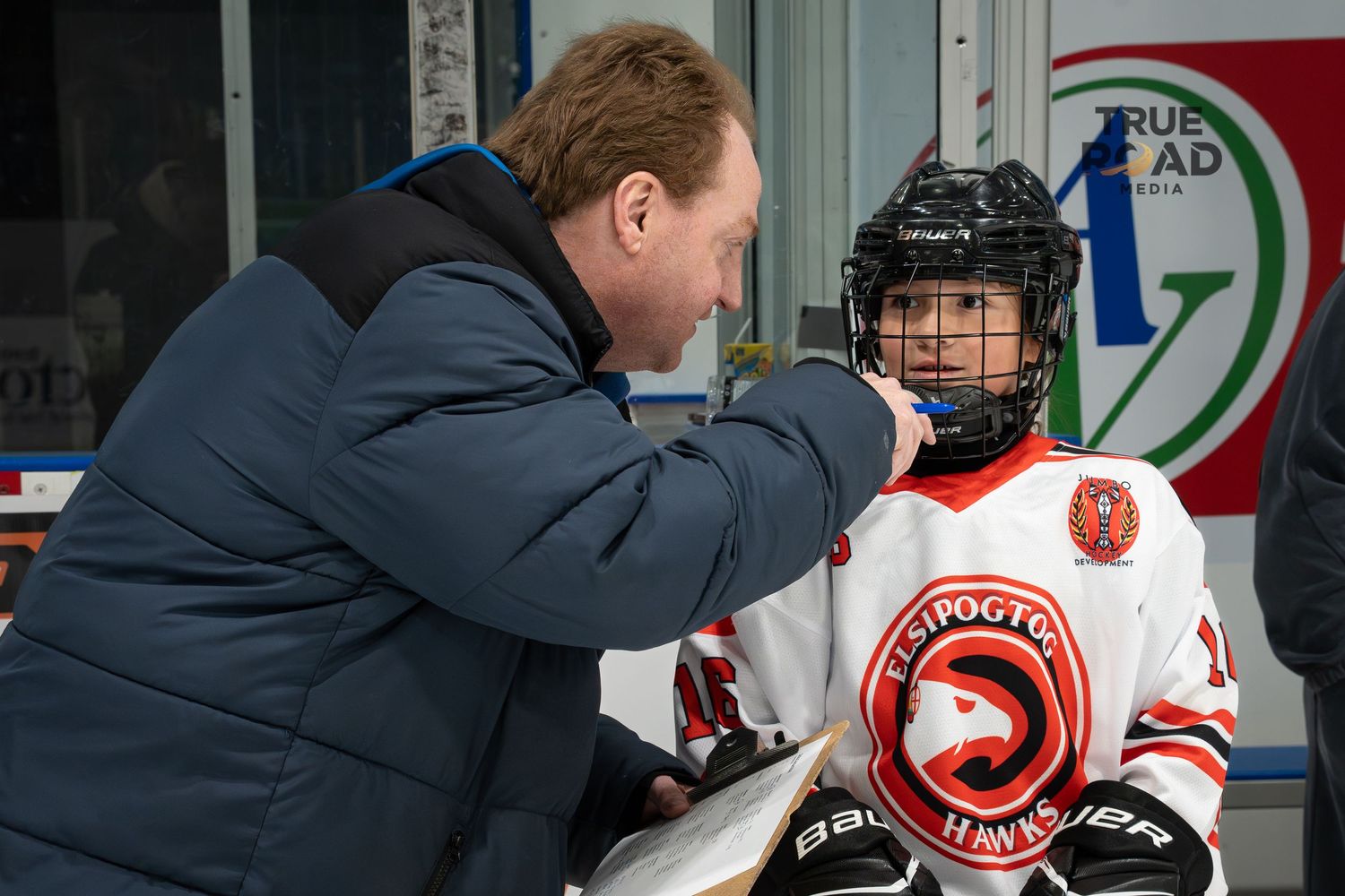 Coach provides guidance to young player during hockey skills training session.