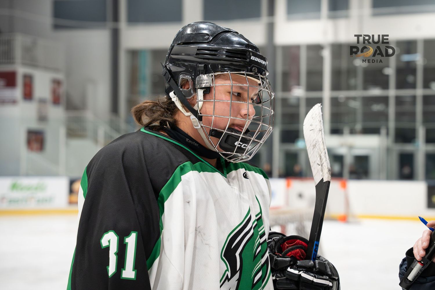 Hockey player in white and green jersey number 91 on the ice during a game.