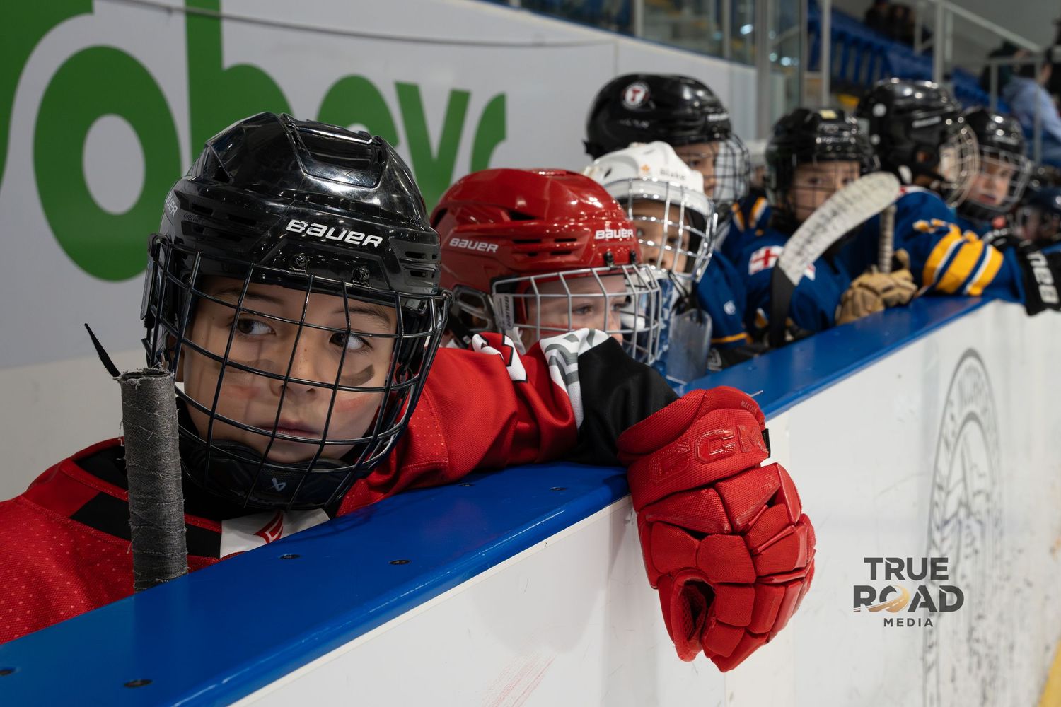 Youth hockey players in helmets and jerseys lined up on the ice during practice or training.