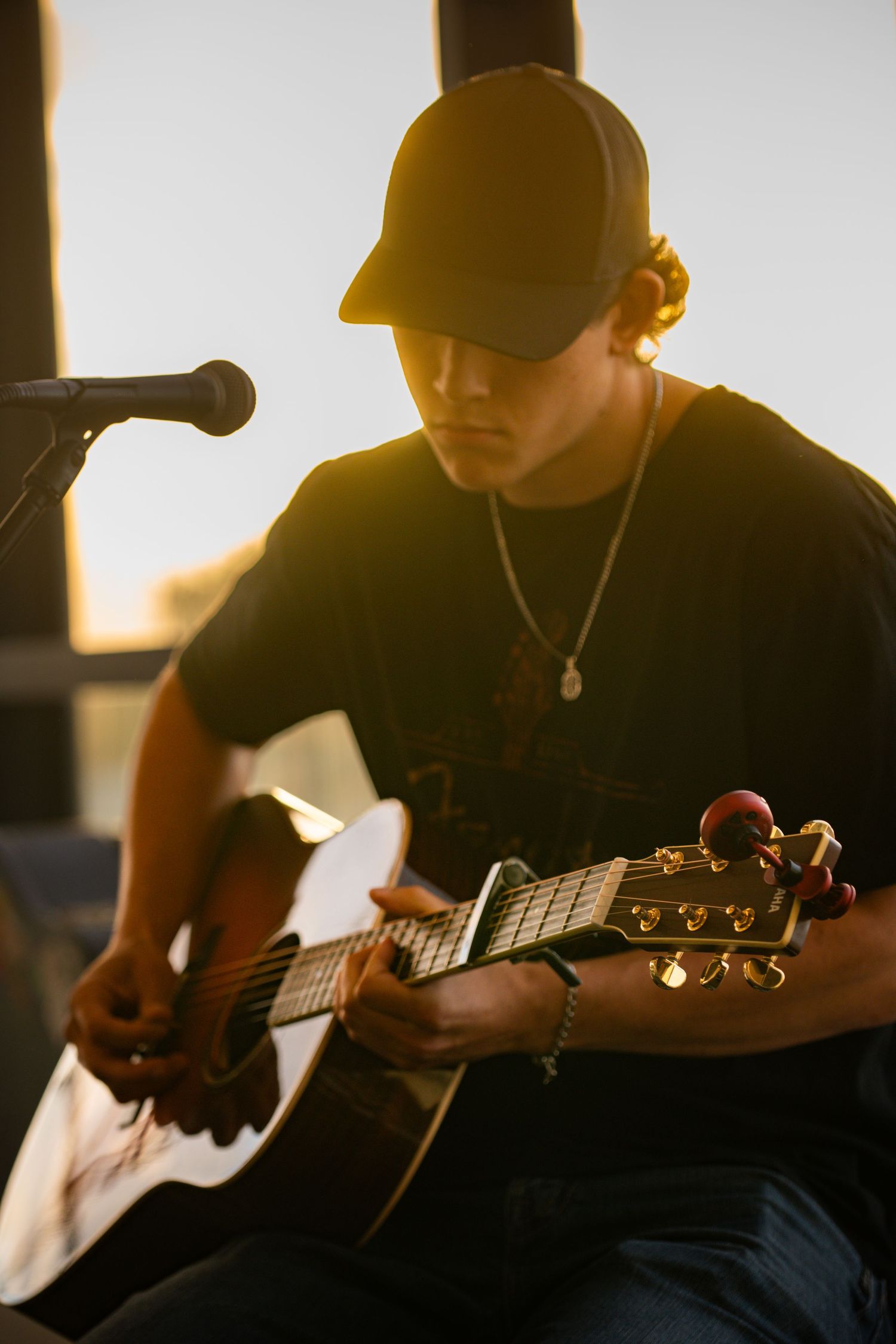 Silhouettes of musicians playing acoustic guitars against a warm sunset background.