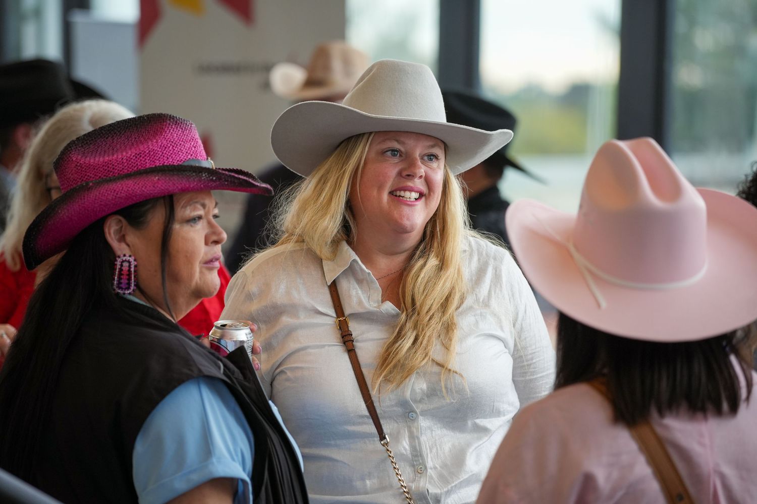 A group of people wearing cowboy hats and western attire gather at an outdoor event.