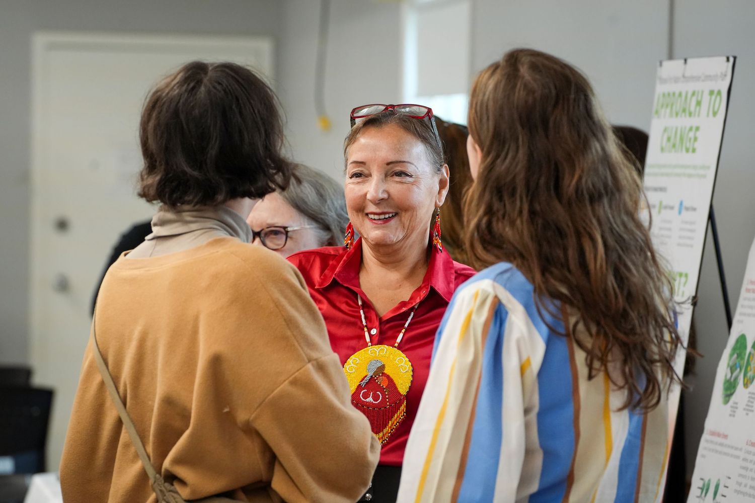 People interacting in an indoor space with bright lighting and informational posters on the wall.