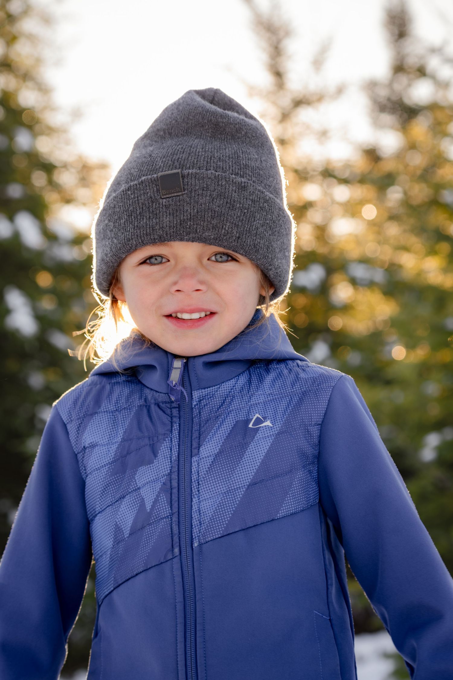 A series of winter portraits showing someone wearing a blue coat and gray beanie hat in snowy outdoor lighting.