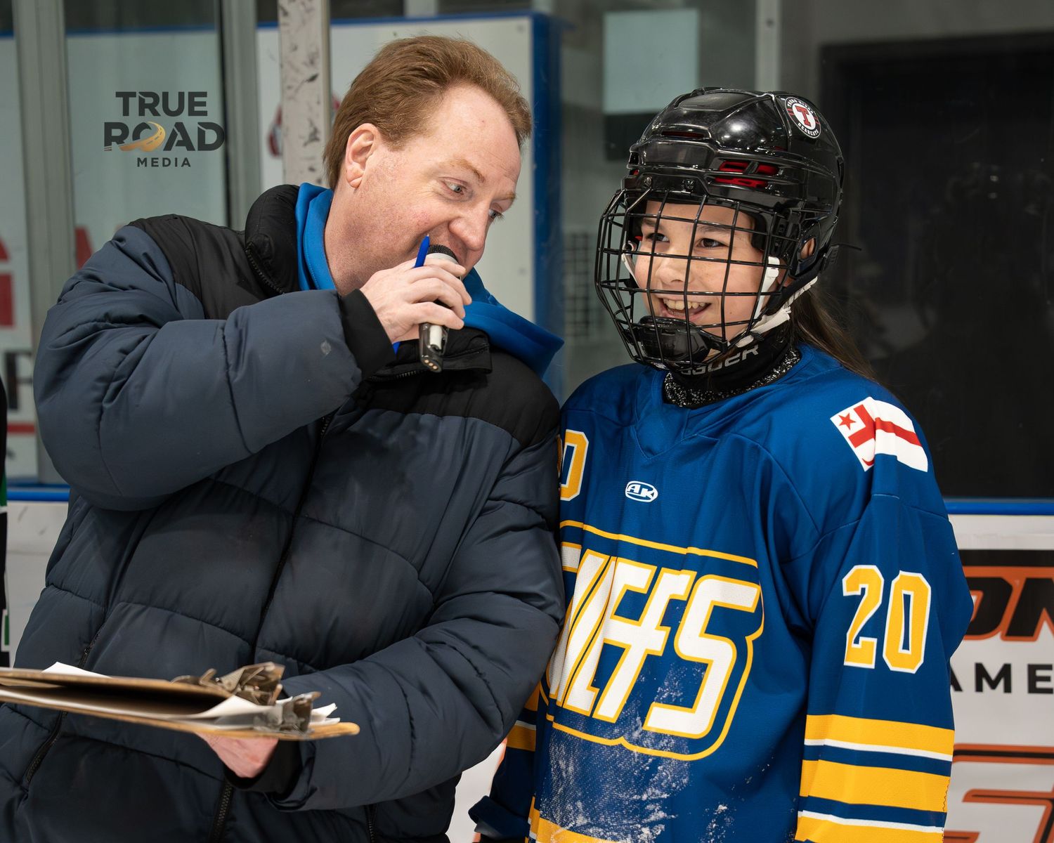 Hockey players in blue and yellow uniforms stand near the team bench during a game.