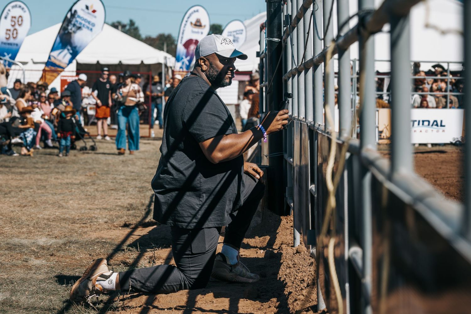 Spectators watch from behind metal barriers at an outdoor sporting event.