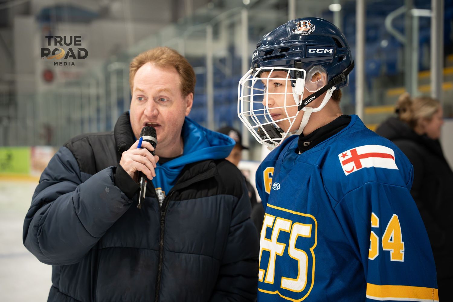 Hockey players in blue uniforms stand near the bench during a game.