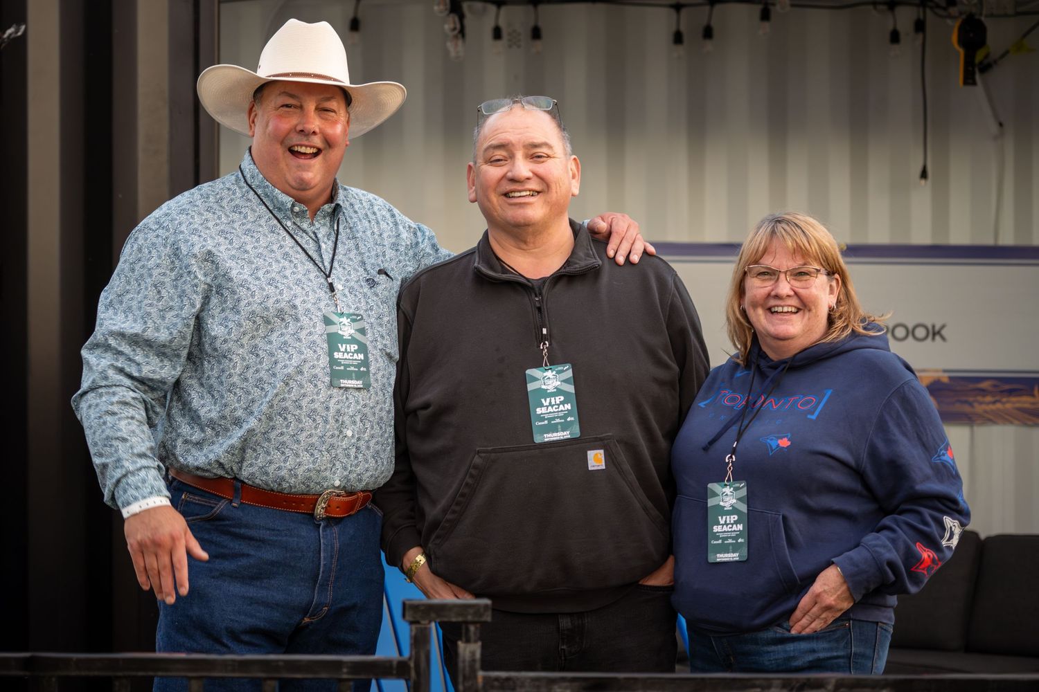People in western attire including cowboy hats gather together at an indoor venue.