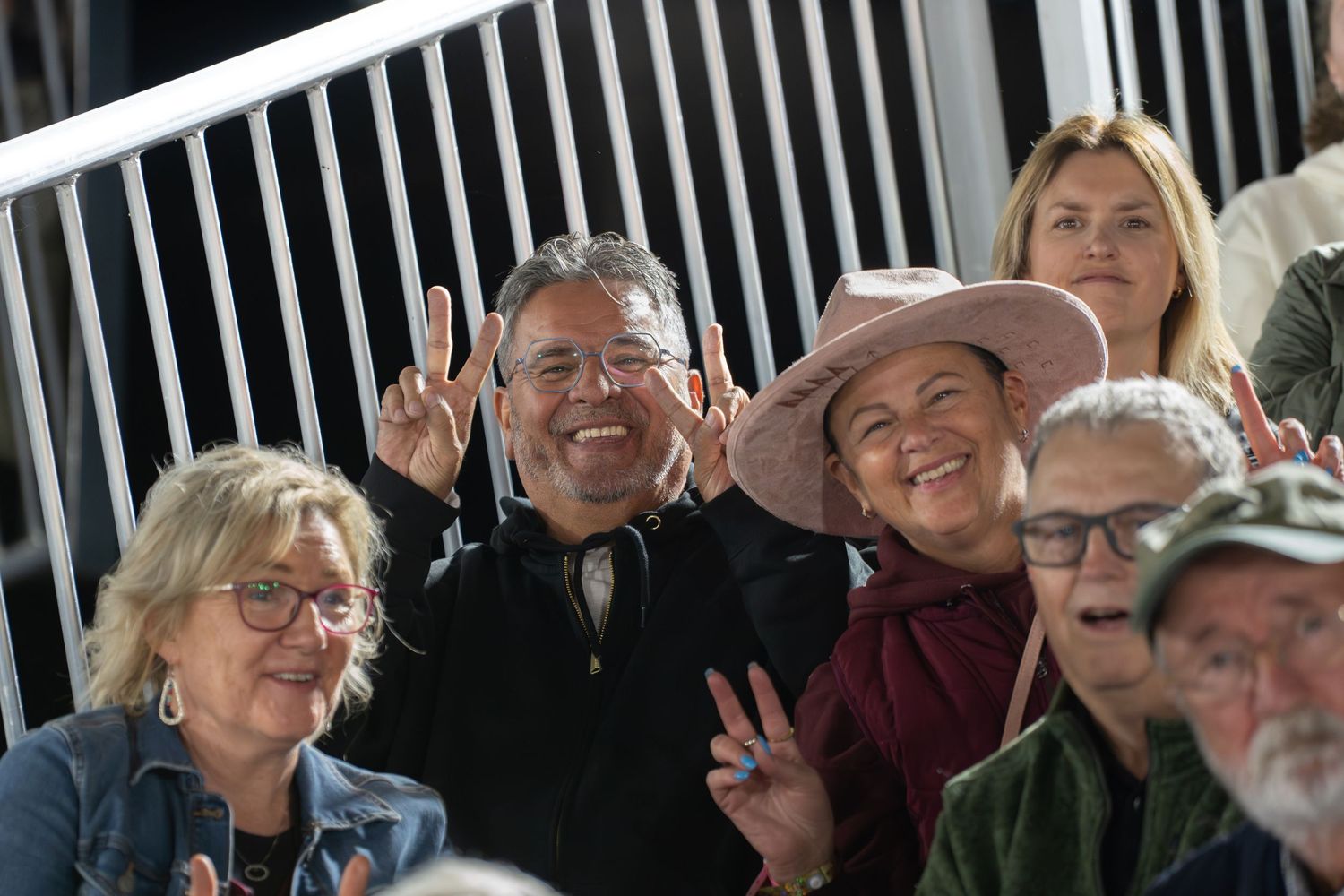 People smiling and socializing in a crowd at an outdoor event.