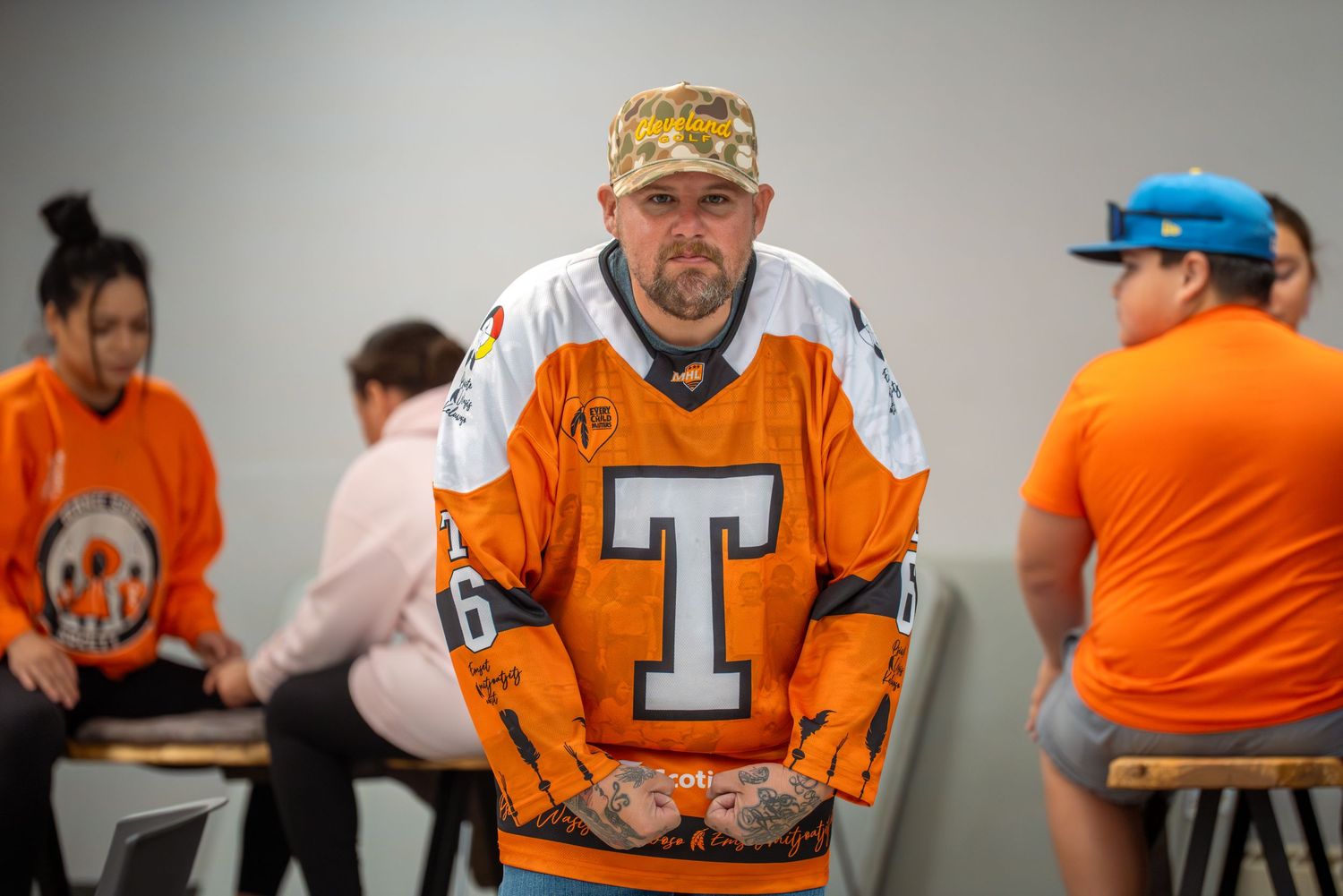 People in orange sports jerseys and casual attire sitting at tables.