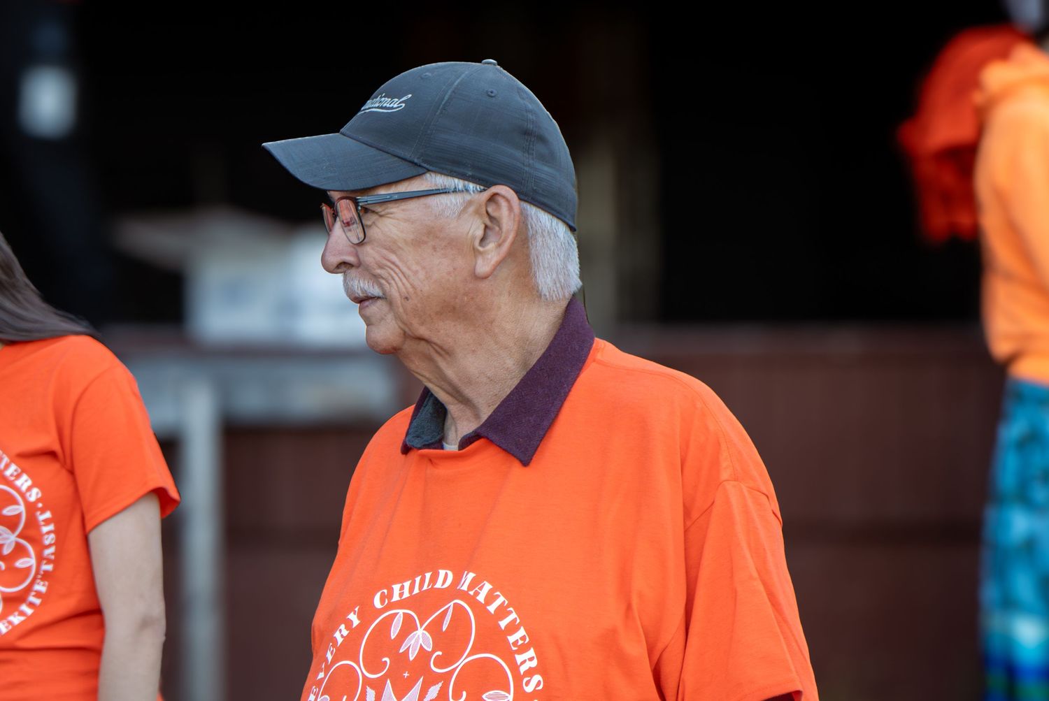 Volunteers in bright orange shirts and baseball caps work together at a community service event.