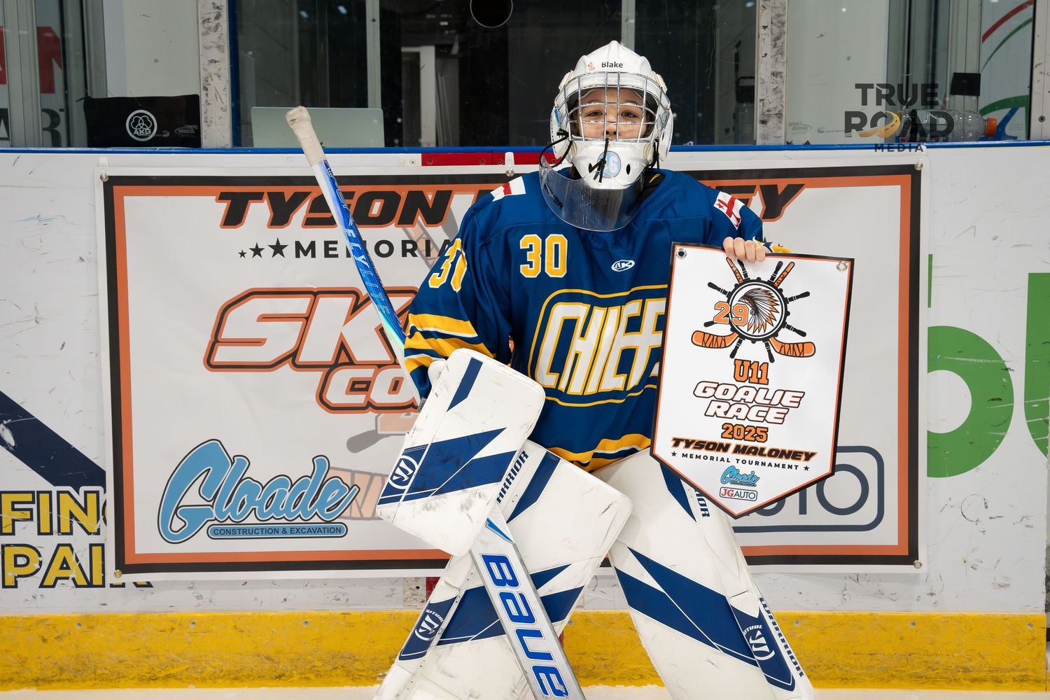 Hockey players in blue and white uniforms practicing on the ice with arena advertisements visible.