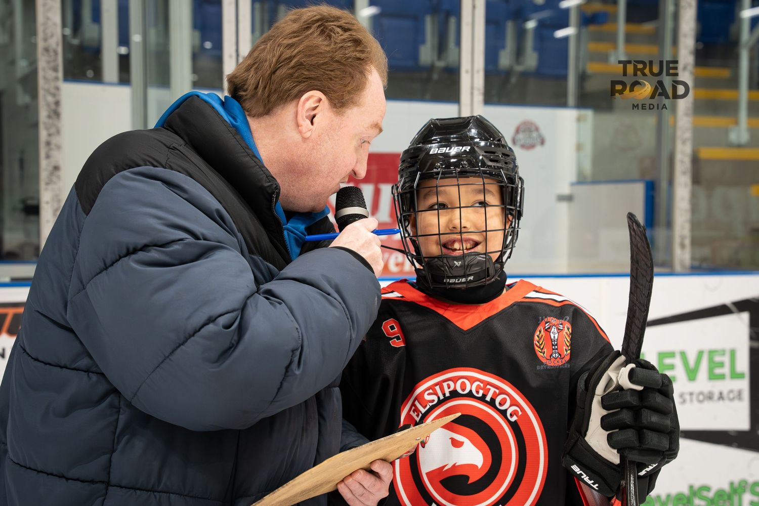 Coach gives instruction to young hockey player in protective gear during skills competition.
