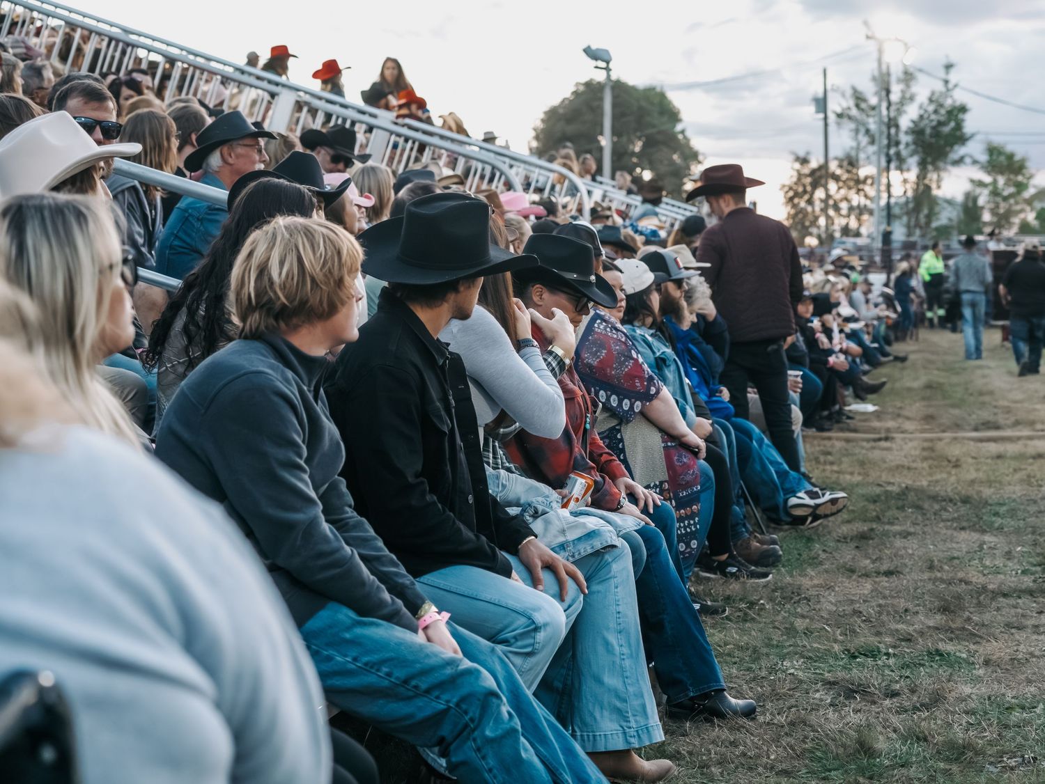 Spectators sitting in outdoor bleachers during a daytime event.