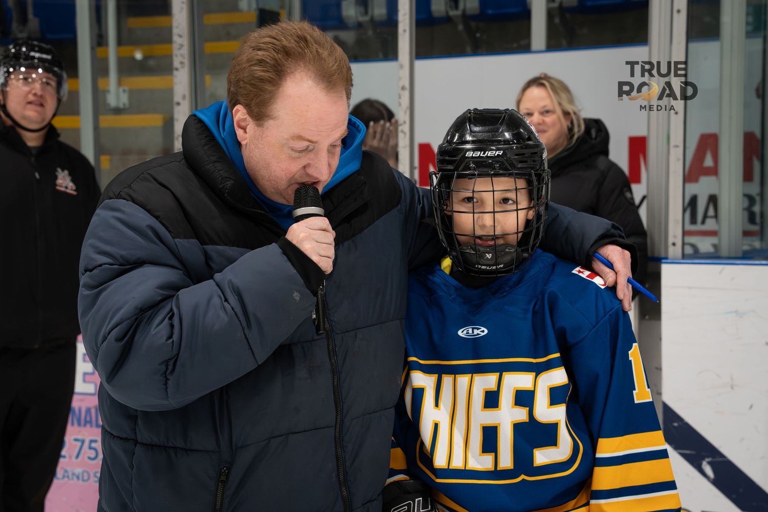 Hockey players and coaches gathered at rink side during practice or game session.