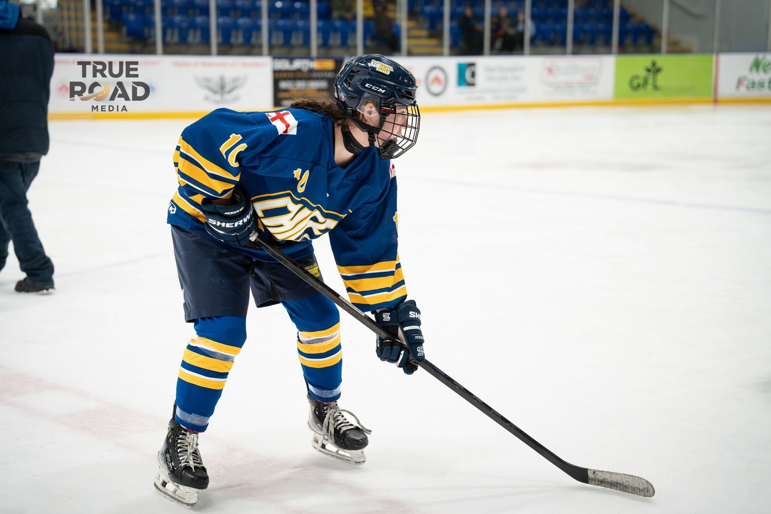 Hockey players in blue and yellow uniforms chase after the puck during an intense game on the ice.