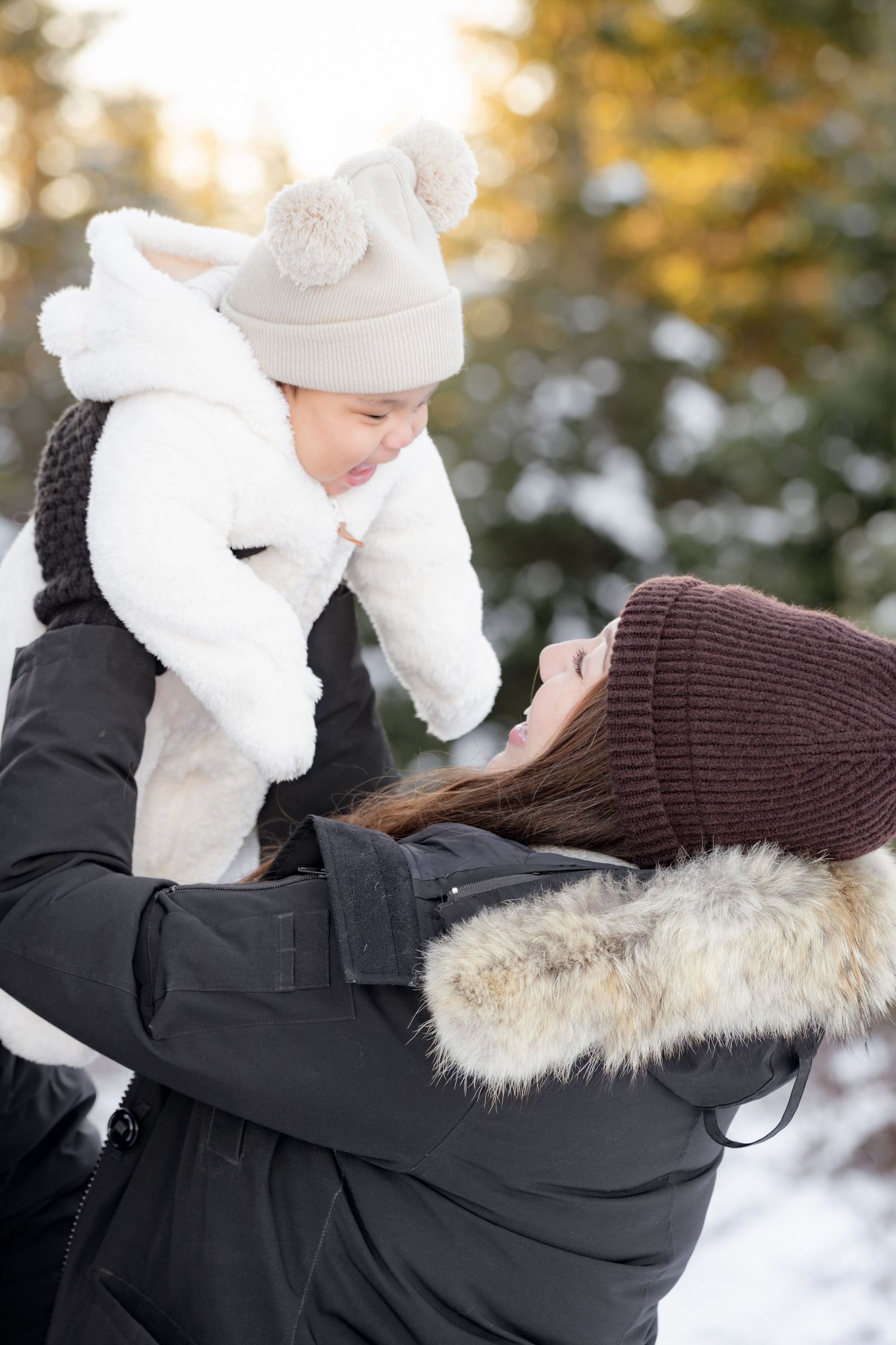 A series of four photos showing someone in a black winter coat with fur trim hood embracing a small figure in white.
