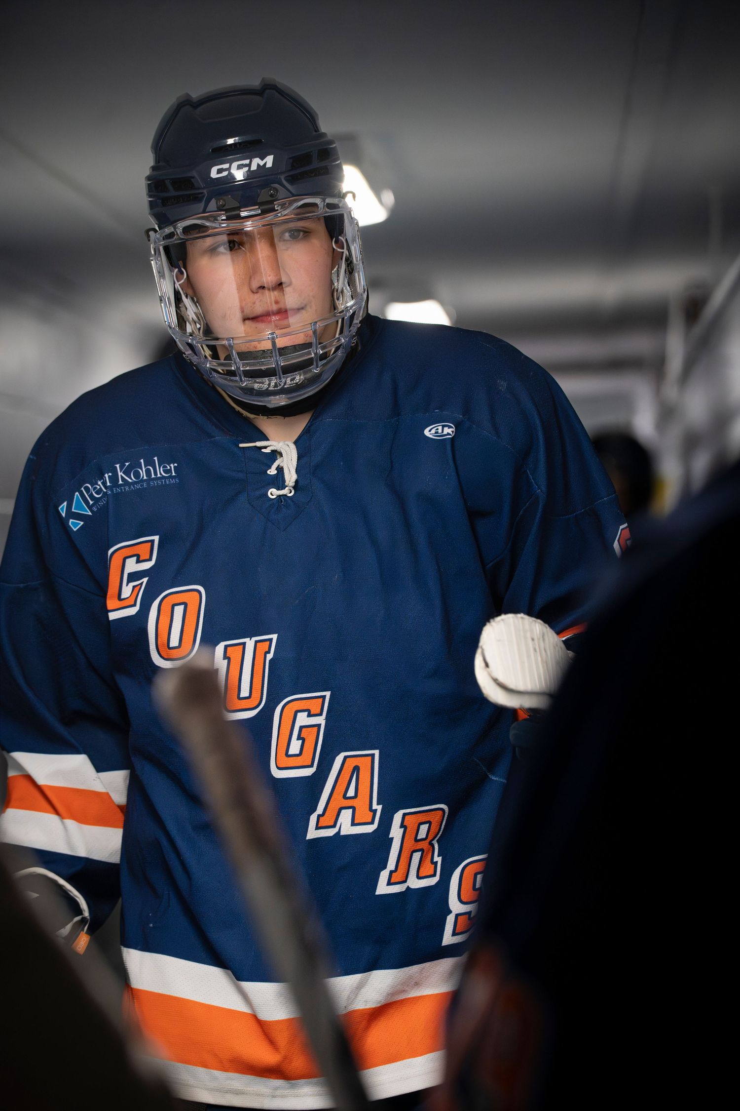 Hockey players in navy blue and orange uniforms with CCM gear during a game or practice session.