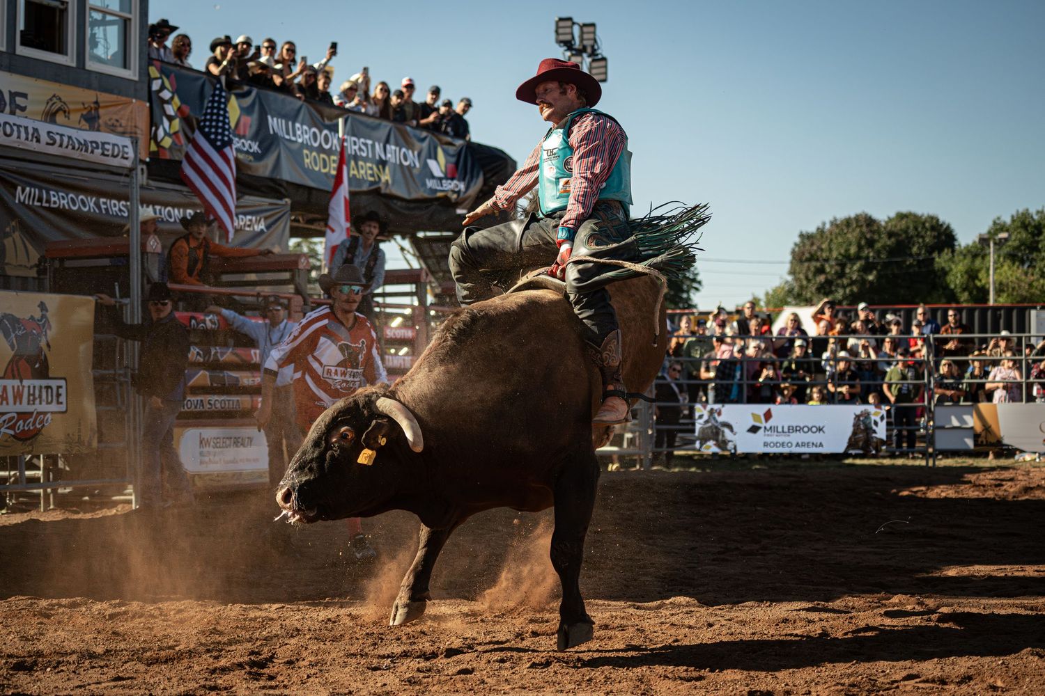 Dramatic action shot of bull riding at outdoor rodeo arena.