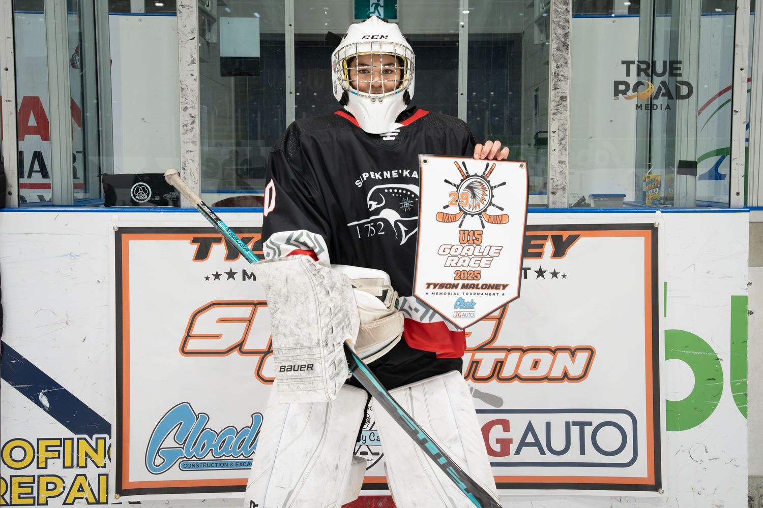 Hockey player in white jersey skates on ice rink with advertisements visible on boards.