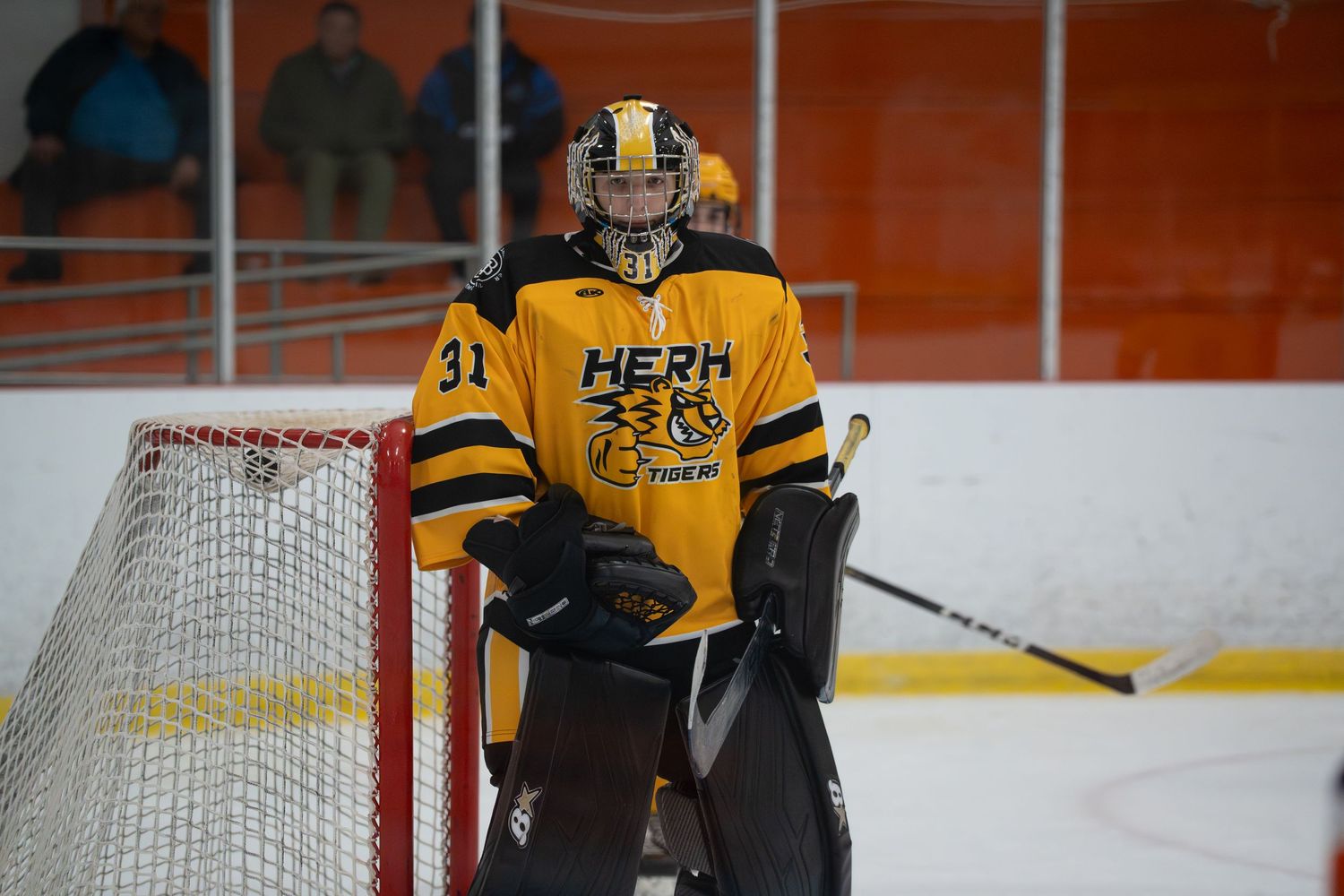 Hockey players in yellow and black jerseys gather near the goal during an ice hockey match.