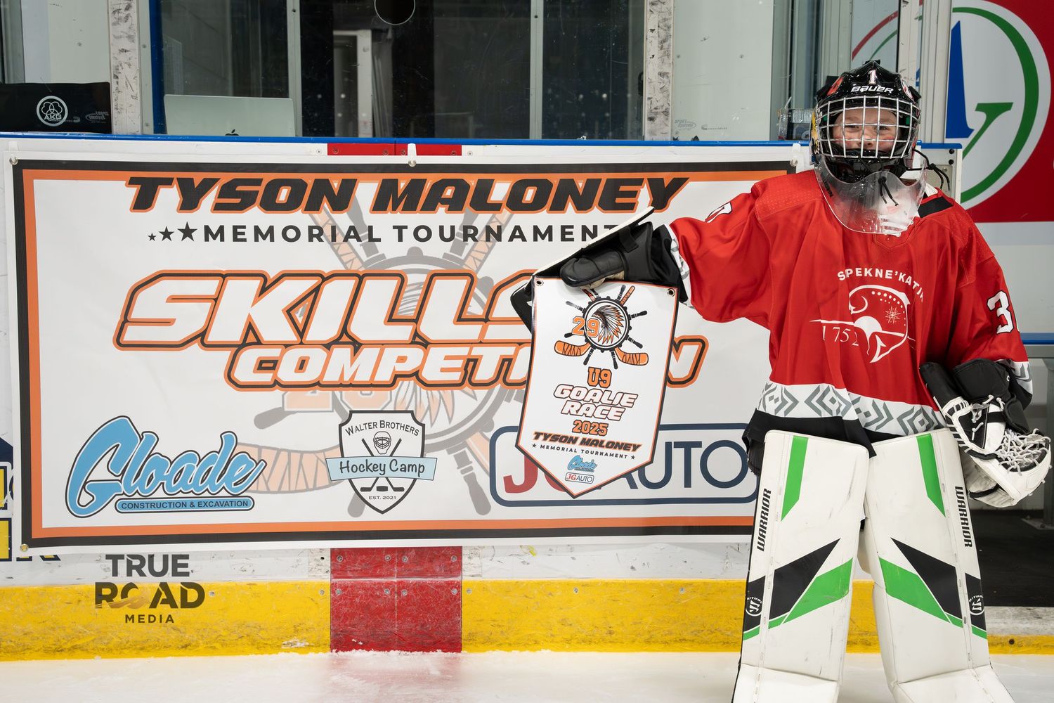 Ice hockey rink with players practicing and various sponsor banners displayed on the boards.