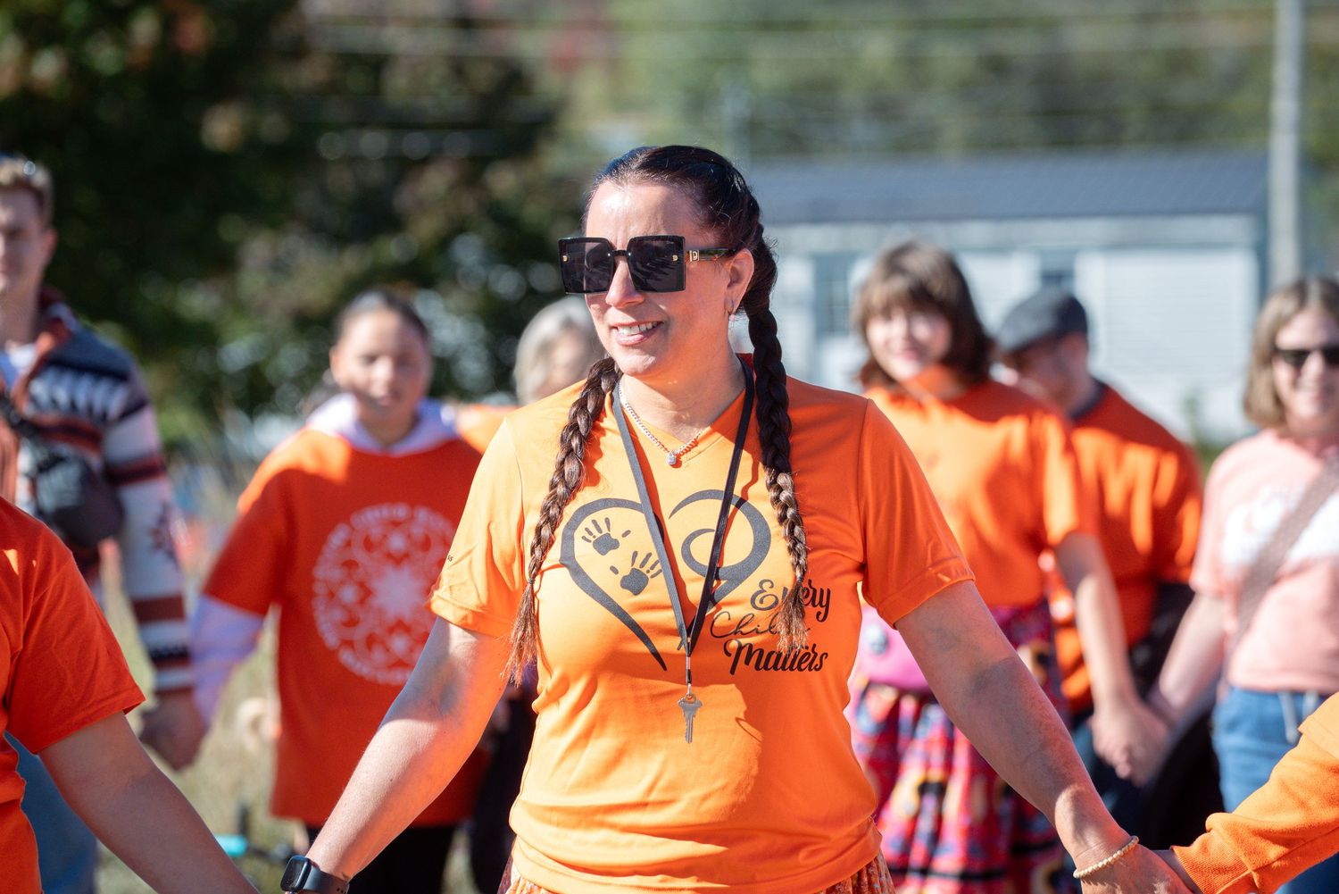 Group wearing bright orange t-shirts at an outdoor event.